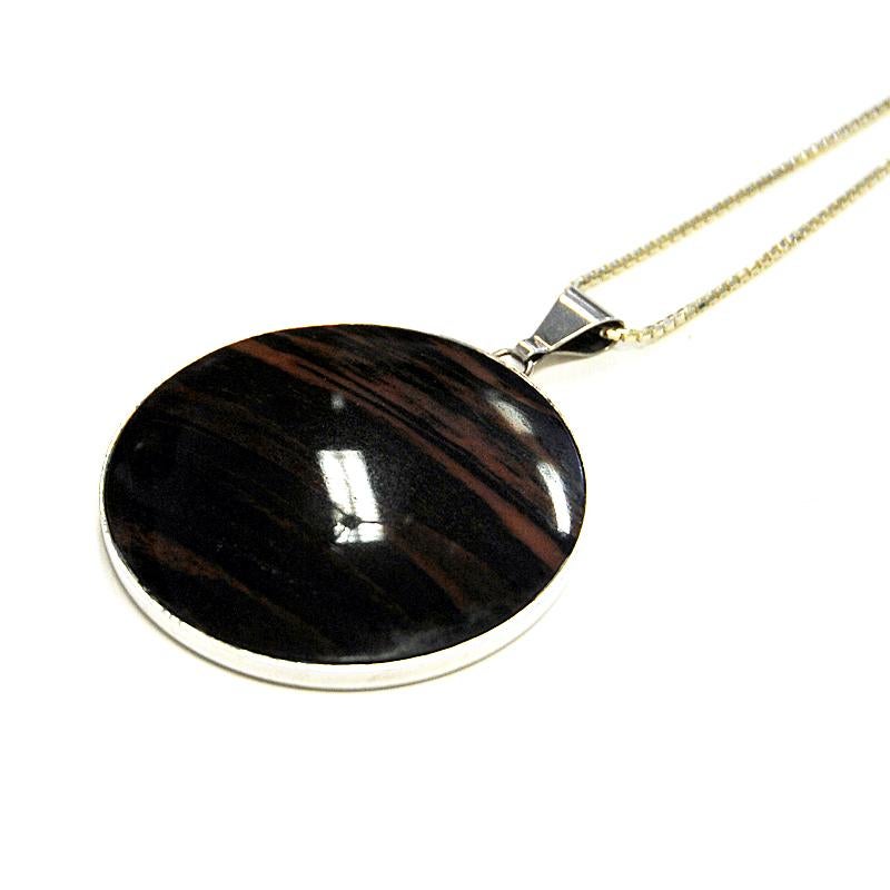 Special black and brown patterned nature stone pendant on a silver chain by Stenlya Bengtsson & Co., 1971, Sweden. The pendant stone has shatters of brown and black stone surrounded by a silver frame. Circular pendant shape. Marked with LYA-S-V9 on