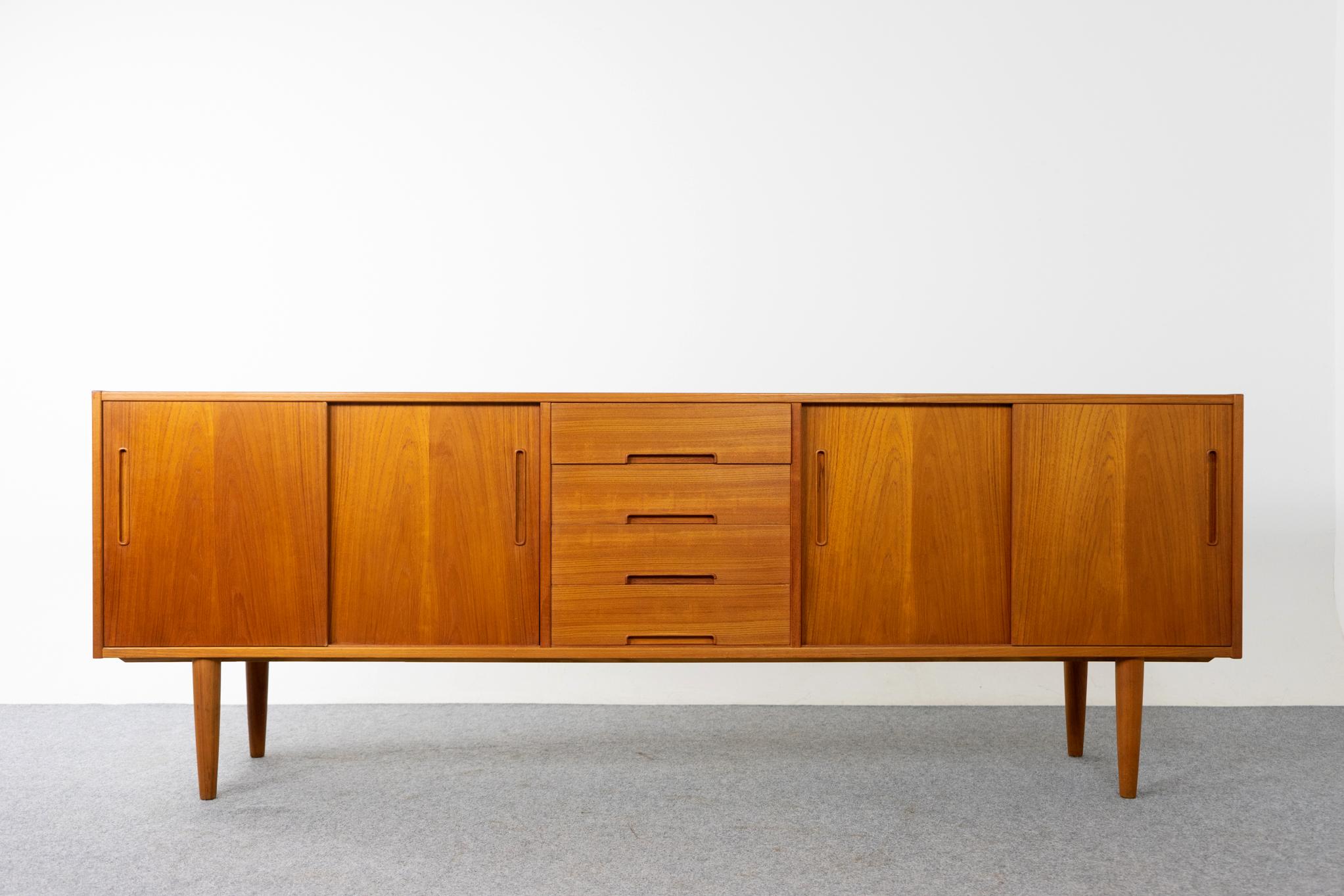 Teak Scandinavian gigant sideboard by Nils Jonsson manufactured by Troeds Bjarnum, circa 1960's. Clean, simple lined design with exceptional book-matched veneer. Smooth sliding doors reveal two adjustable shelves that can be hung at ten different