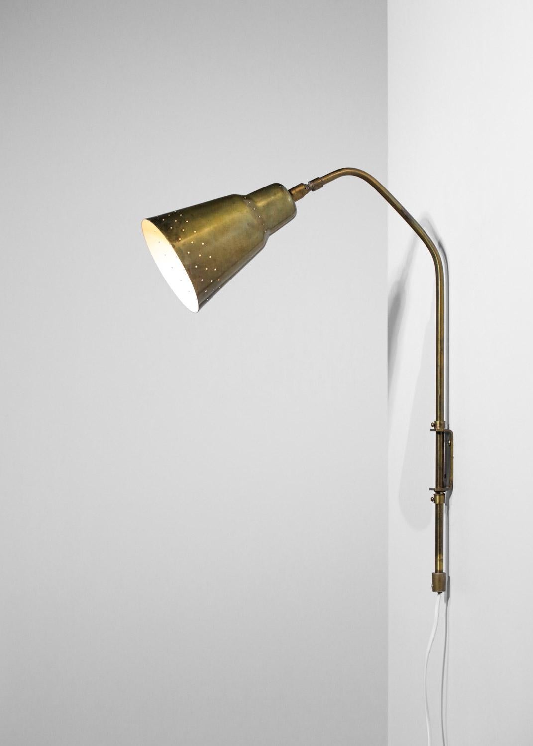 Scandinavian wall lamp edited in the 50's by the Swedish company Bergboms. Structure of the sconce and the lampshade in solid brass, perforated at the level of the lampshade. Possibility to orientate the wall lamp thanks to the ball joint at the