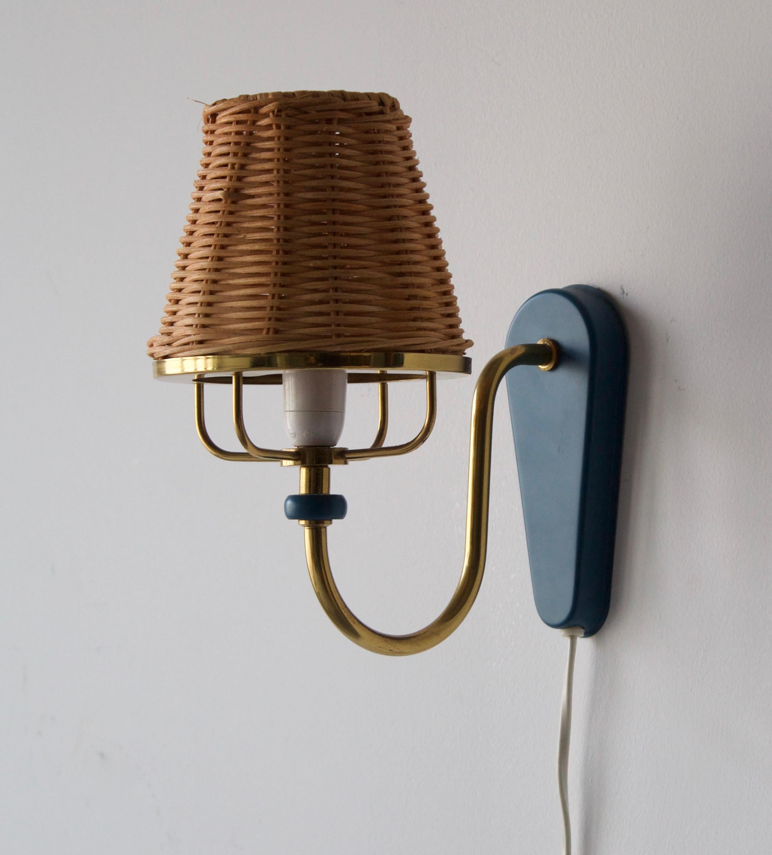 A pair of wall lights, designed and produced in Sweden, 1970s. In brass, blue lacquered metal, assorted rattan lampshades.

No stated max wattage on fixture, not UL-listed. Currently configured per original execution as plug-in. Please consult
