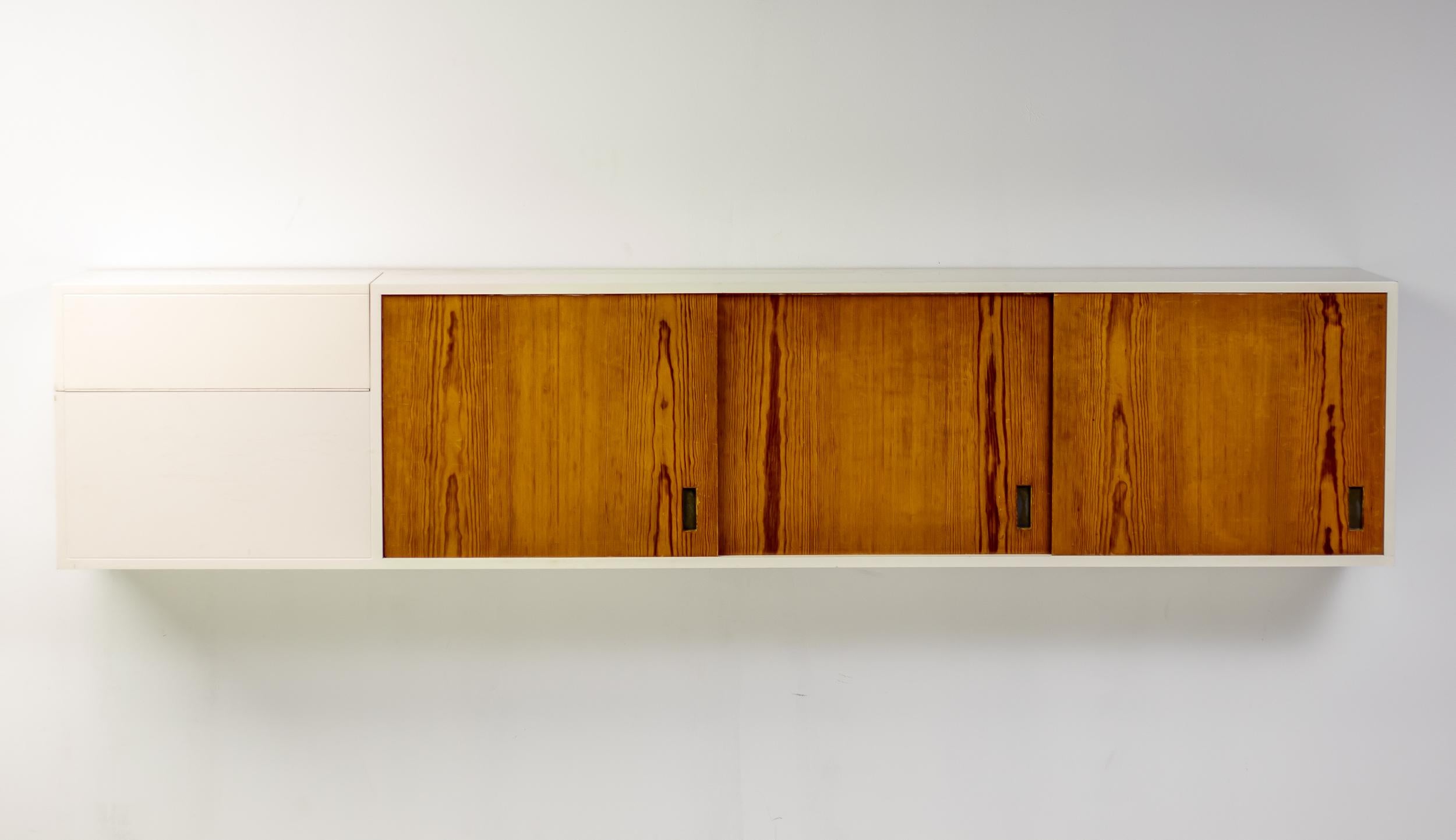 This wonderful and unique modernist Swedish wall mounted cabinet in nicely aged pure white lacquered plywood and Oregon Pine matches the practical design ideas of Florence Knoll with the pure basic aesthetics of Axel Einar Hjorth. The best of both