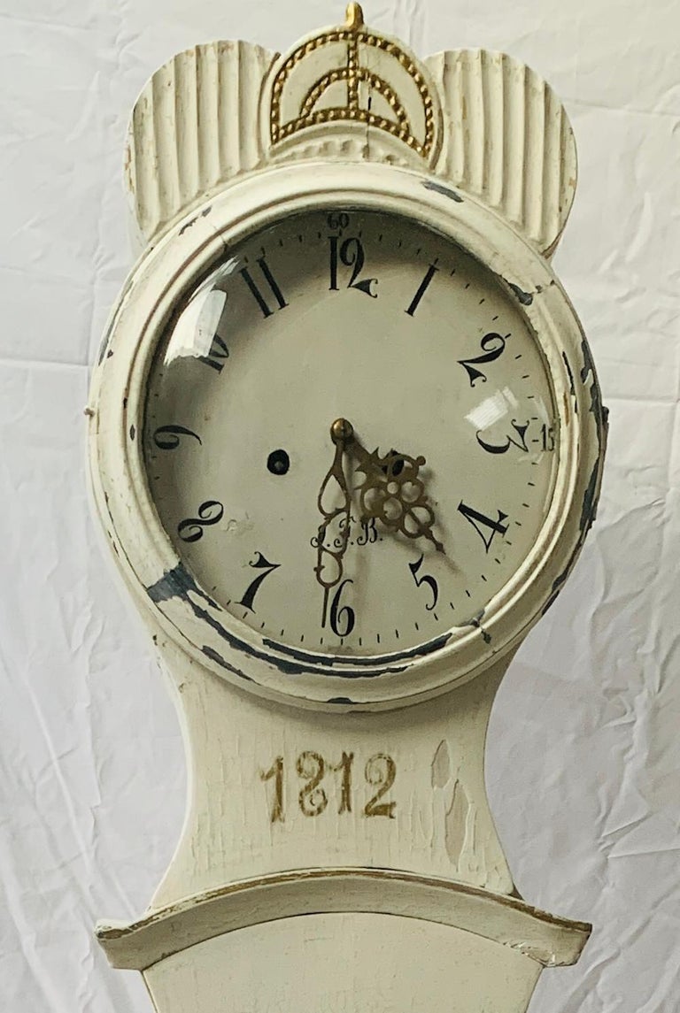 Early 1800s antique Swedish mora clock in white paint with Classic Fryksdal inspired carved detailing on the body and hood. This grandfather mora clock is extremely unusual in its decoration and carved detailing. It has lovely wear on teh base