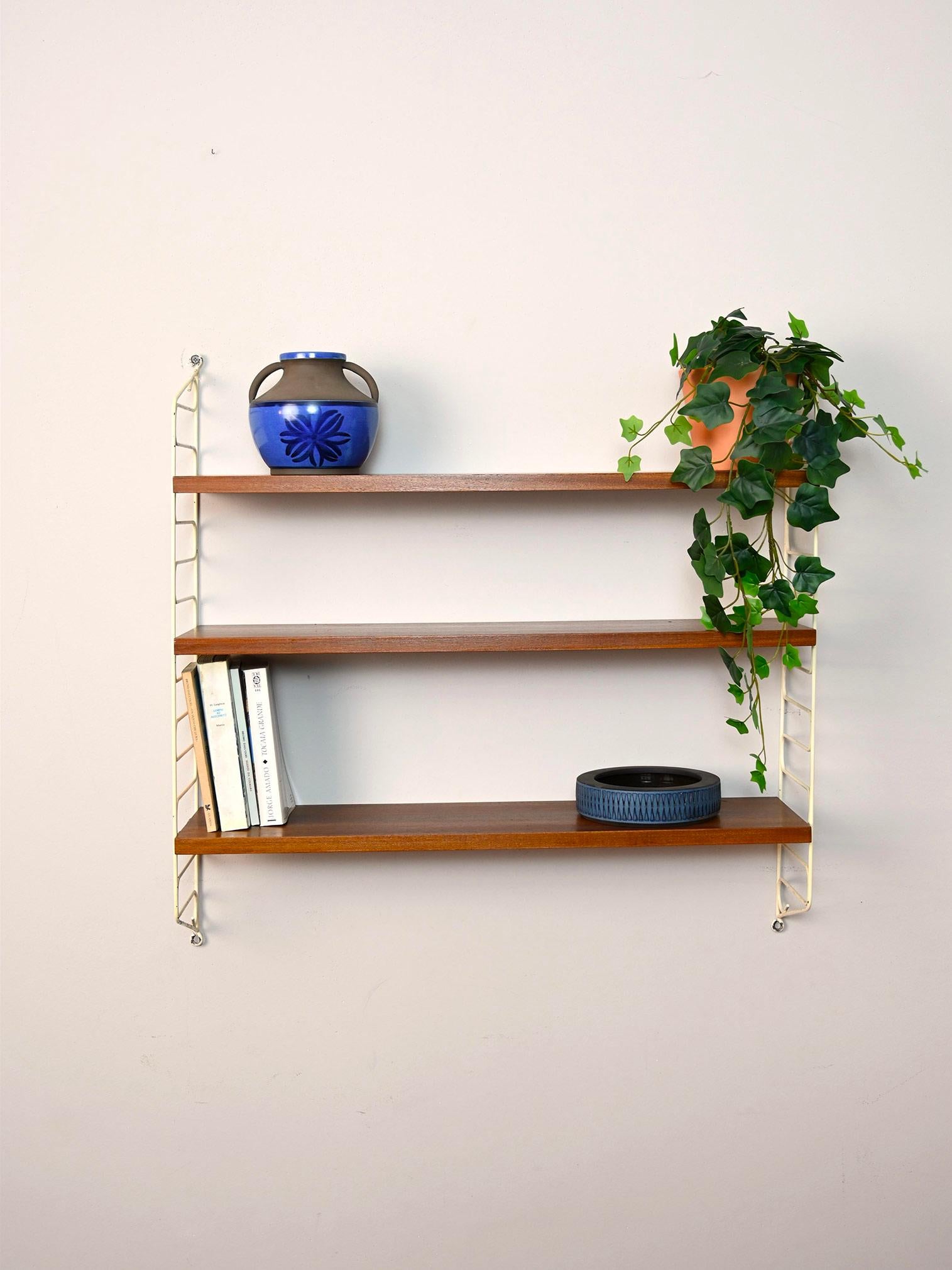 1960s Scandinavian bookcase.

This simple shelving system consists of a coated metal side frame on which three wooden shelves fit.
Simple and functional it can be hung in different rooms of the house.

Good condition. It has been restored with