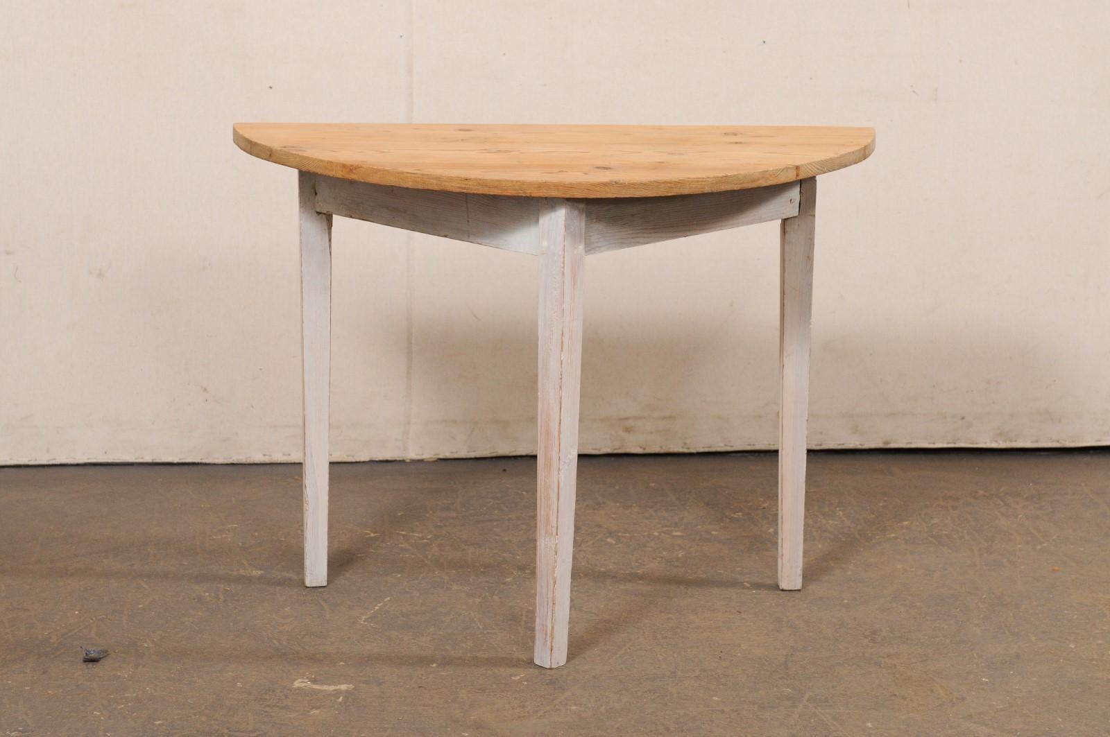 A Swedish single bleached-wood and painted demi-lune table from the mid 20th century. This vintage table from Sweden features a semi-circular top over a plain triangular shaped apron, and is raised upon three squared and gently tapered legs. The