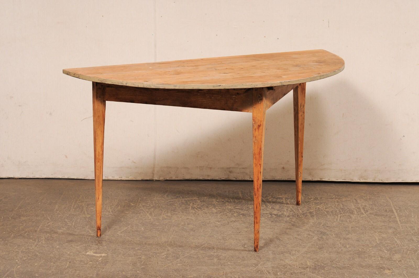 A single Swedish wooden demi-lune console table from the early 20th century. This antique table from Sweden features a semi-circular, or half moon top, over a triangular shaped apron. The skirt is clean and plain, and the piece is raised upon three