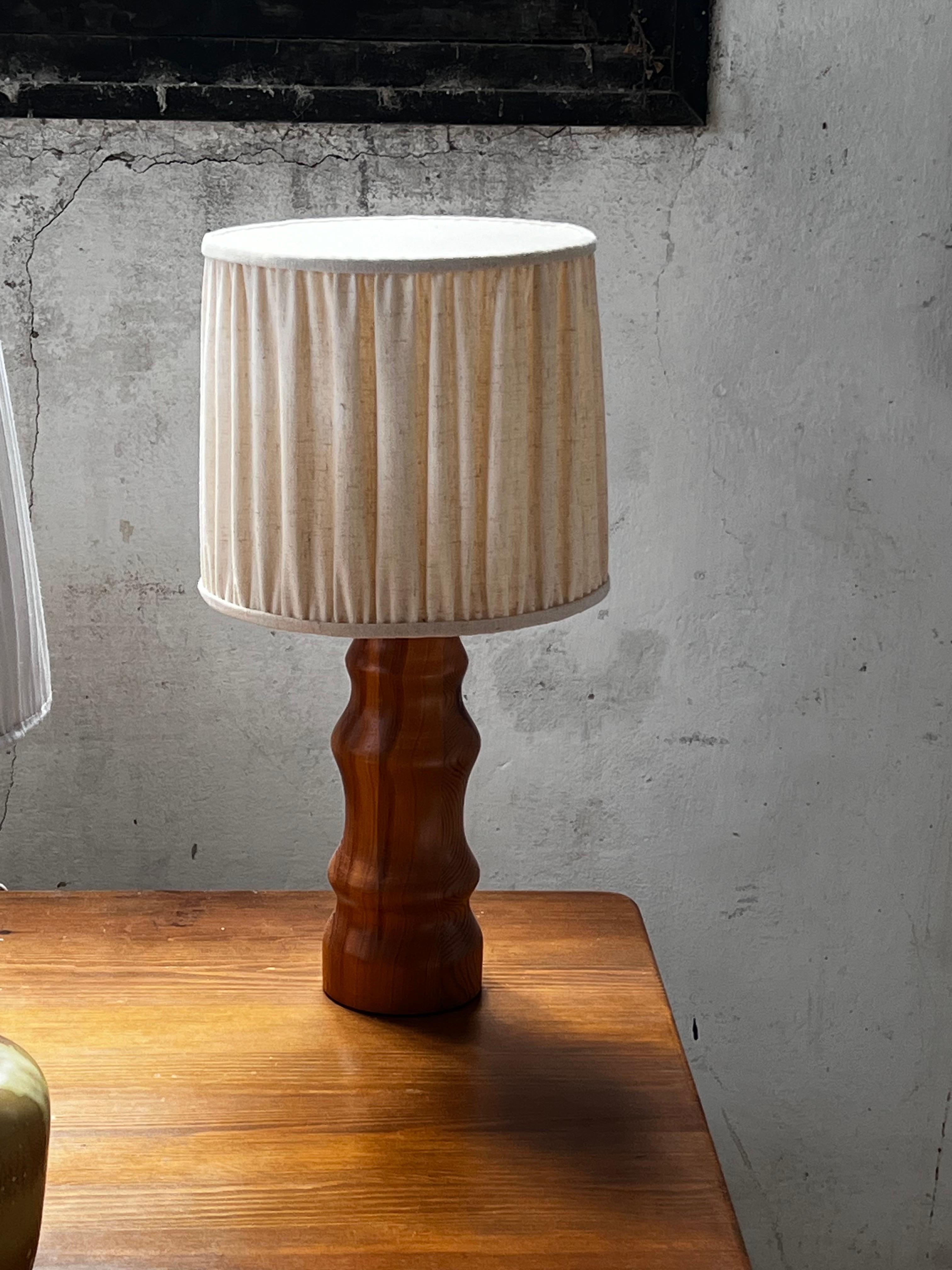 Lampe décorative en bois dur fabriquée dans les années 1970 en Suède. Fabriqué en bois dur dans une base de forme sculpturale. La hauteur totale de cette lampe, y compris l'abat-jour, est de 51 cm. L'abat-jour a une hauteur de 23 cm et un diamètre