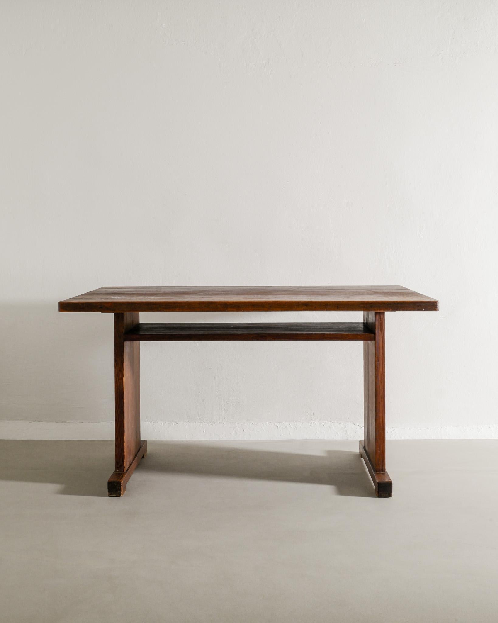 Seltener hölzerner Ess-/Arbeitstisch mit Regal aus dunkel gebeiztem Kiefernholz, Axel Einar Hjorth zugeschrieben, hergestellt in Schweden, 1930er Jahre. 
In gutem Originalzustand. 

Abmessungen: H: 76 cm / 29.90