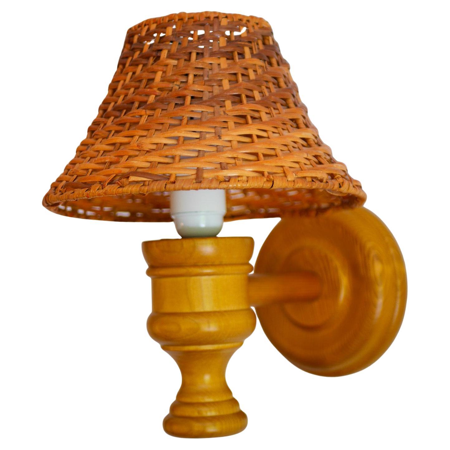 Rustic and substantial, this large handmade wooden sconce with a rattan lampshade, which was crafted from solid pine by Smålandsslöjd, Sweden, and designed by Stig Johnson — a celebrated artisan known for his lamps, distinctive bowls, candlesticks,