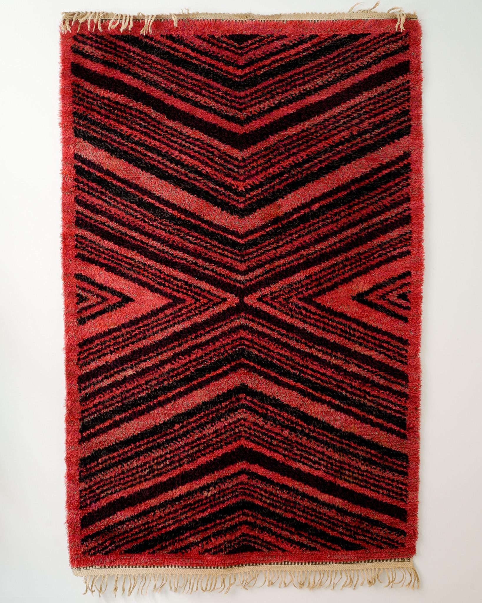 Rare Swedish mid century carpet / rug in shaggy red and black wool by the well known designer Barbro Nilsson produced by Märta Måås-Fjetterström, 1940s. In good original condition, some missing fringes. 
Signed 
