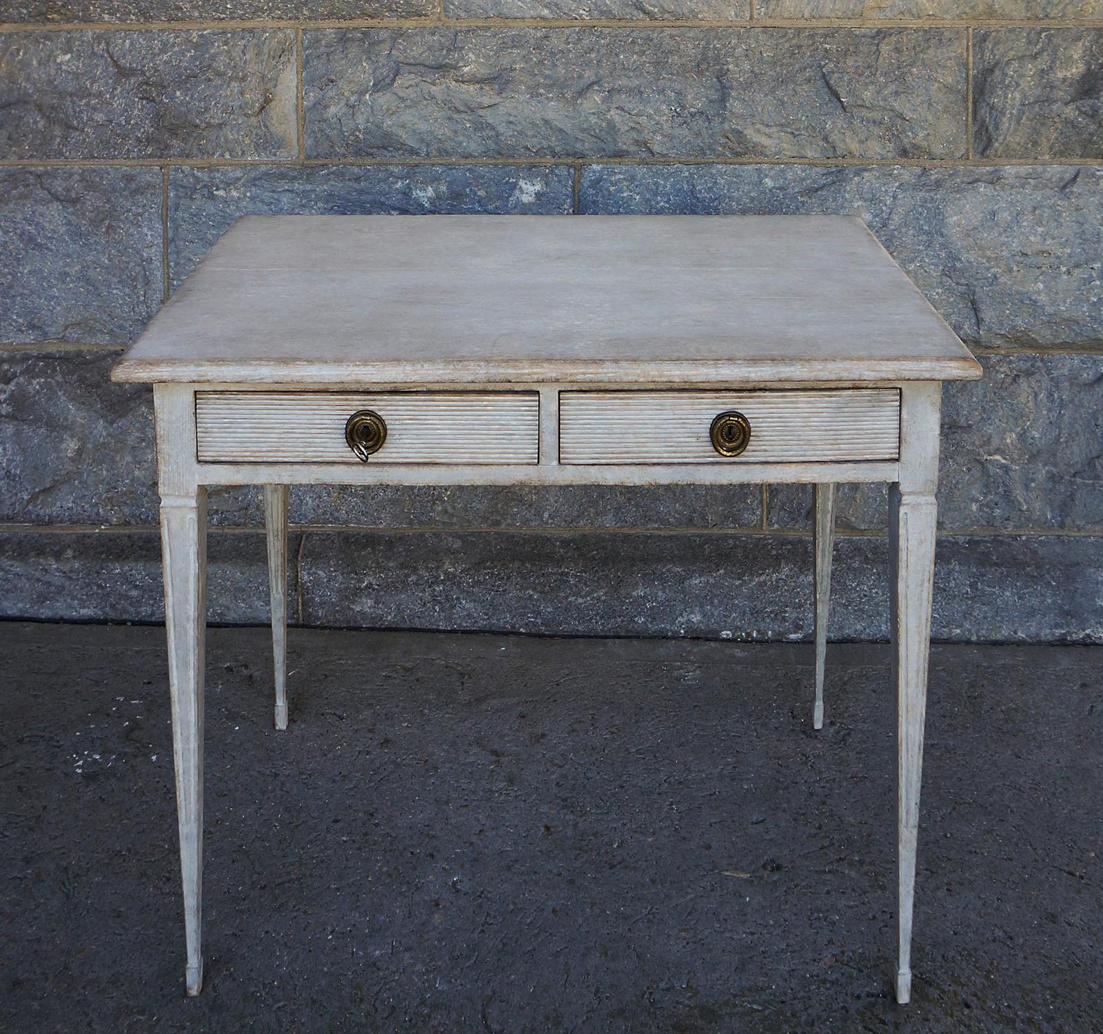 Gustavian style writing table, Sweden circa 1880, with two reeded apron drawers and tapering square legs with delicate spade feet. Brass pulls with integrated locks. Its finished back allows it to be used in a free-standing position.