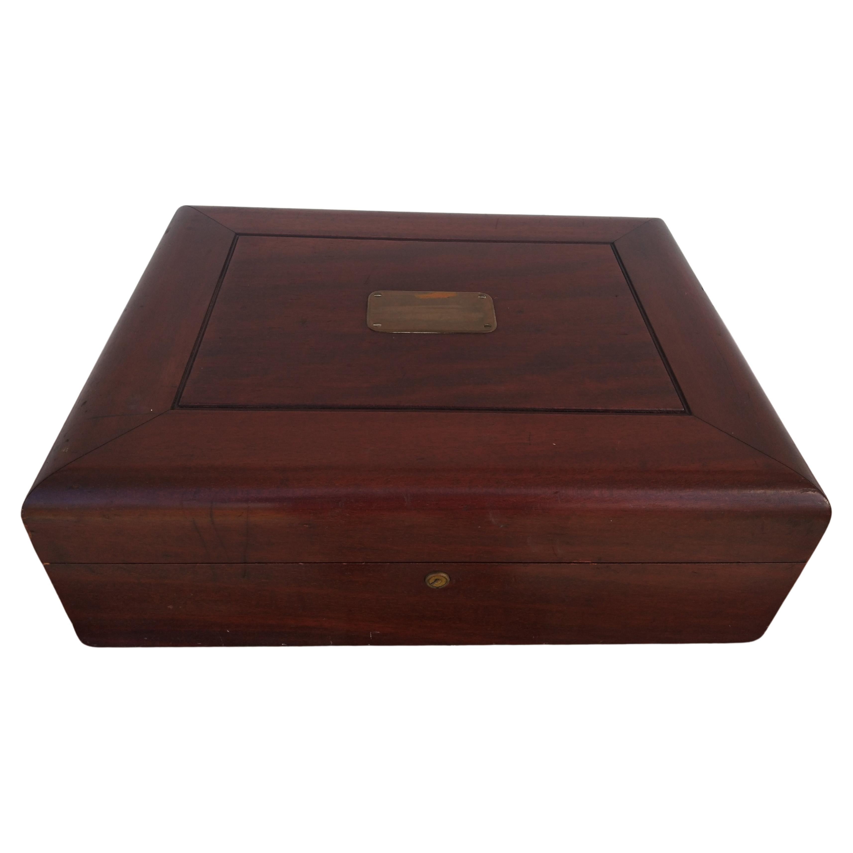 This is a finely crafted silverware box made from mahogany. It has a brass plate top and brass plate side handles.  The interior is made of a rich green velour.