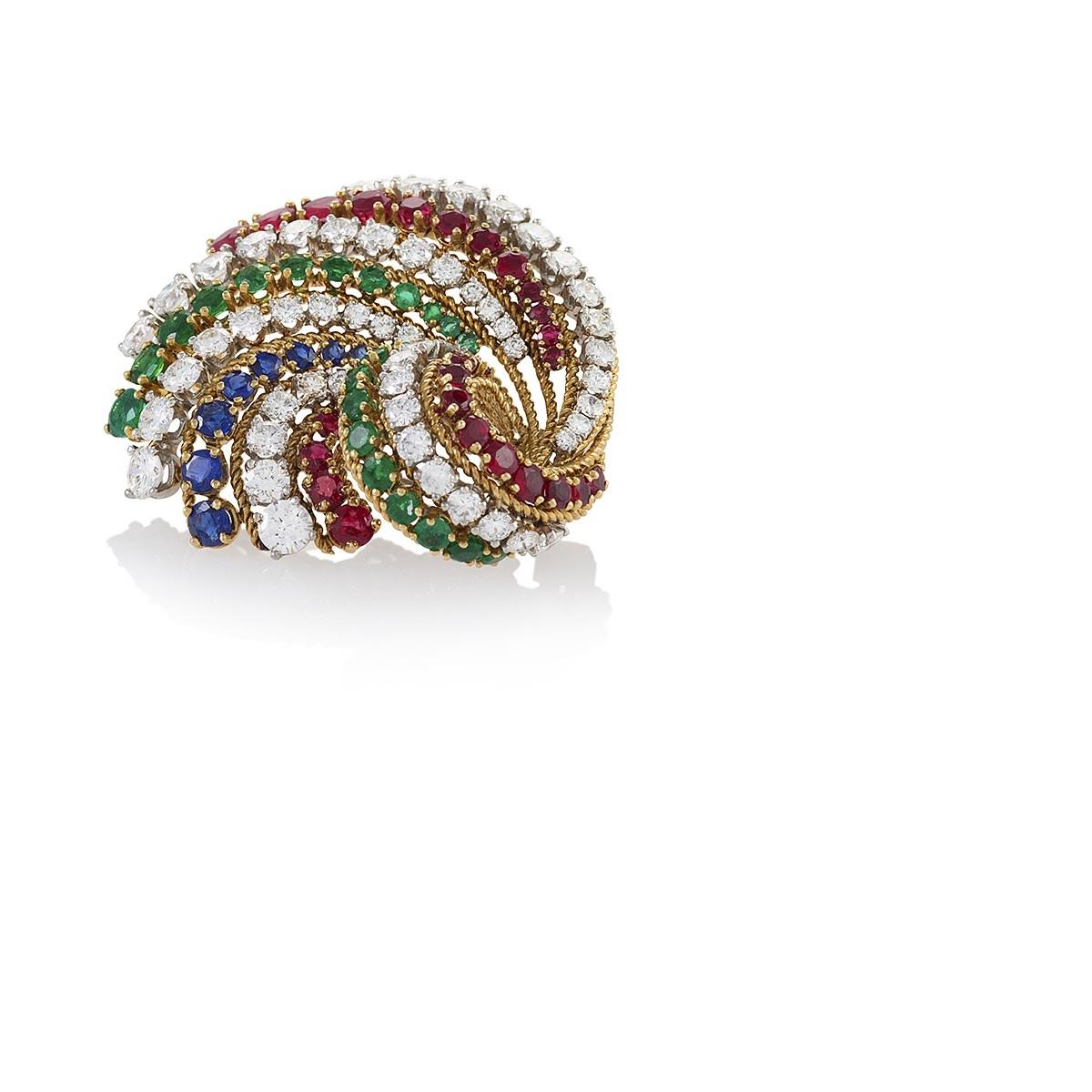 This high-volume swirling ribbon brooch of delicate wirework from Van Cleef & Arpels Paris is set with beautifully matched diamonds, rubies, emeralds, and sapphires, the quartet of noble stones in a sweeping and boisterous display of color. A