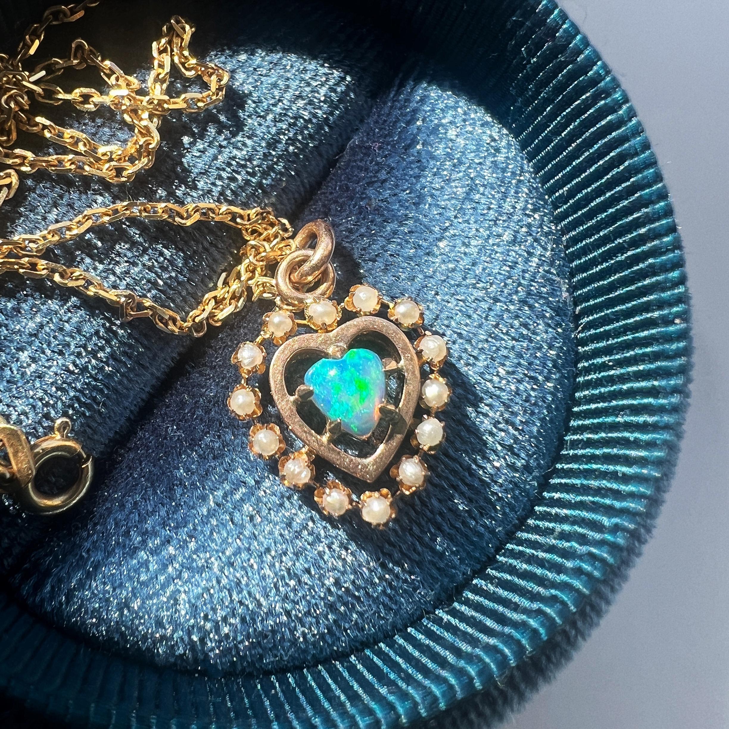 For sale a very sweet pendant featuring a lovely heart-shaped opal cabochon. The opal conveys a strong play-of-fire with a rainbow flash of mainly blue and green hues. Surrounding the opal is a delicate circle of lustrous 14 white seed pearls, which