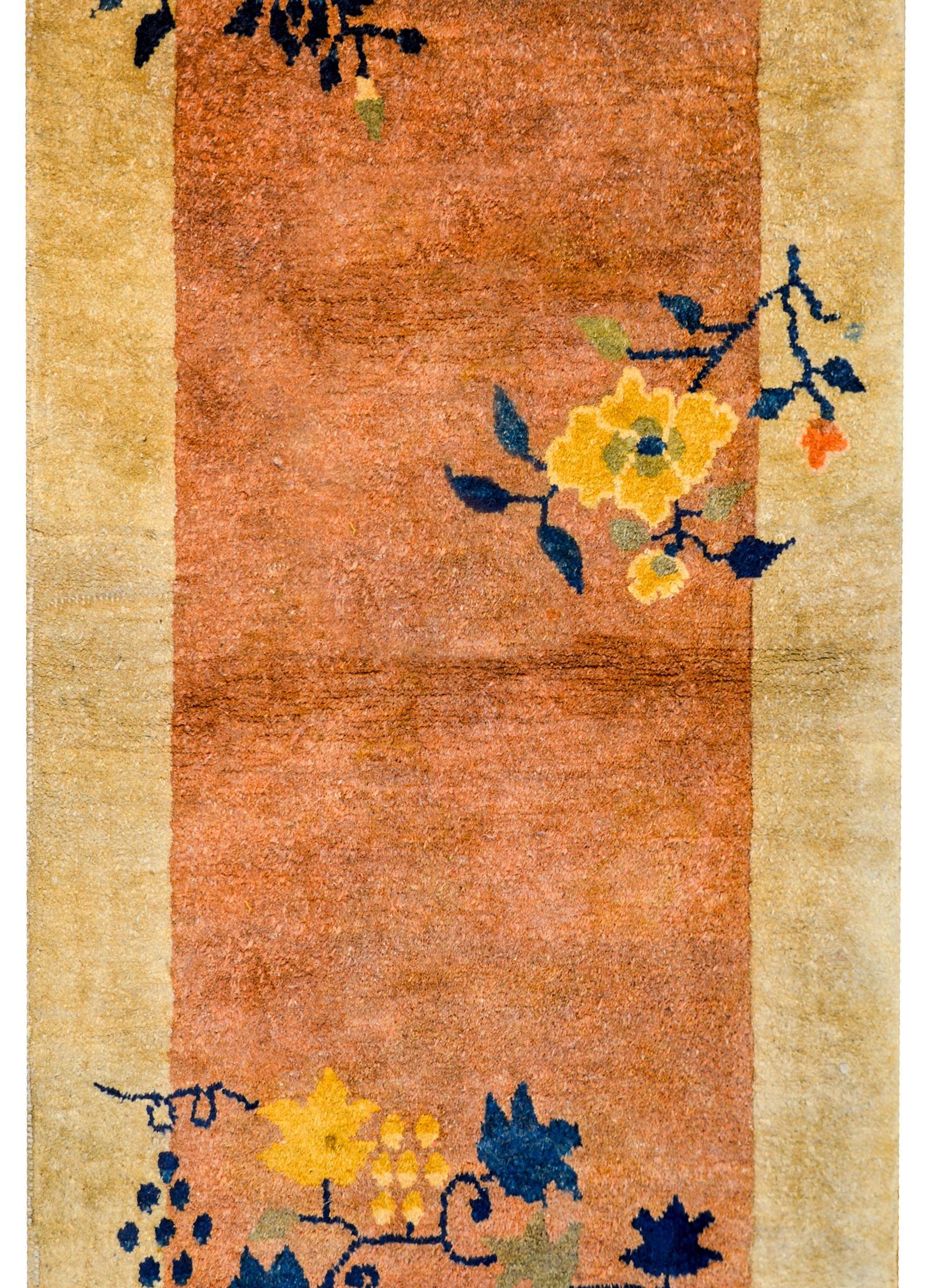 A sweet early 20th century Chinese Art Deco rug with a peach field surrounded by a wide taupe border. A bright yellow peony, blue chrysanthemum, and several grape clusters surround the field.
