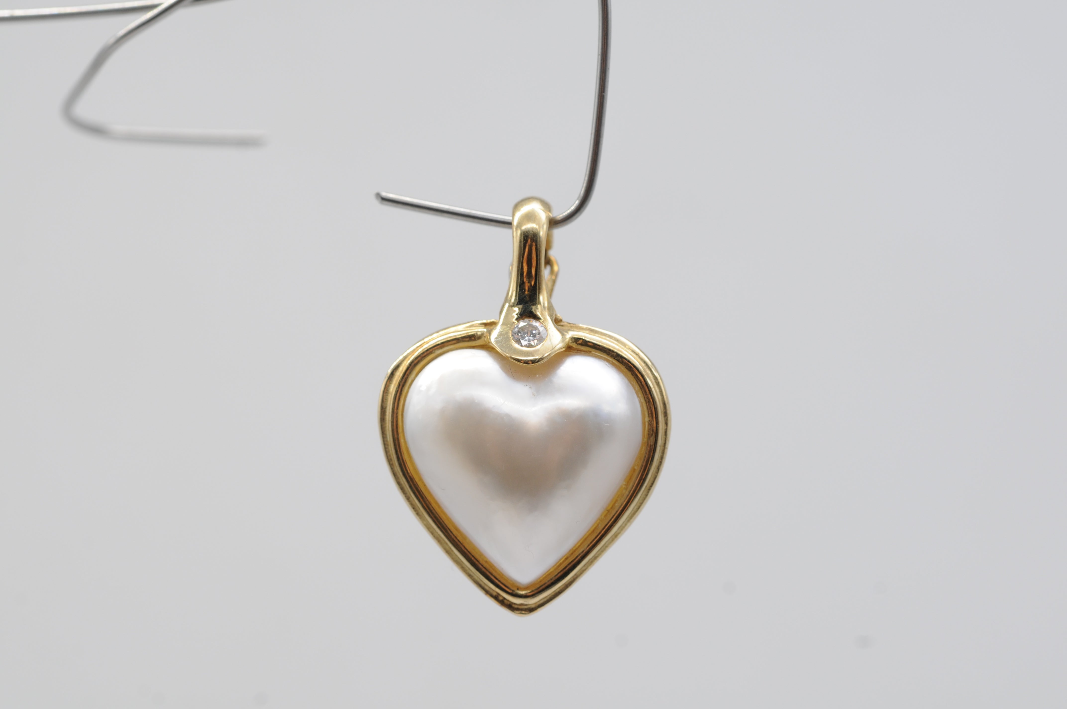 
Enter the realm of exquisite elegance with this enchanting 14k yellow gold pendant, a true masterpiece of craftsmanship and sophistication. Gracing its center is a captivating heart-shaped pearl, delicately coated with iridescent mother-of-pearl,
