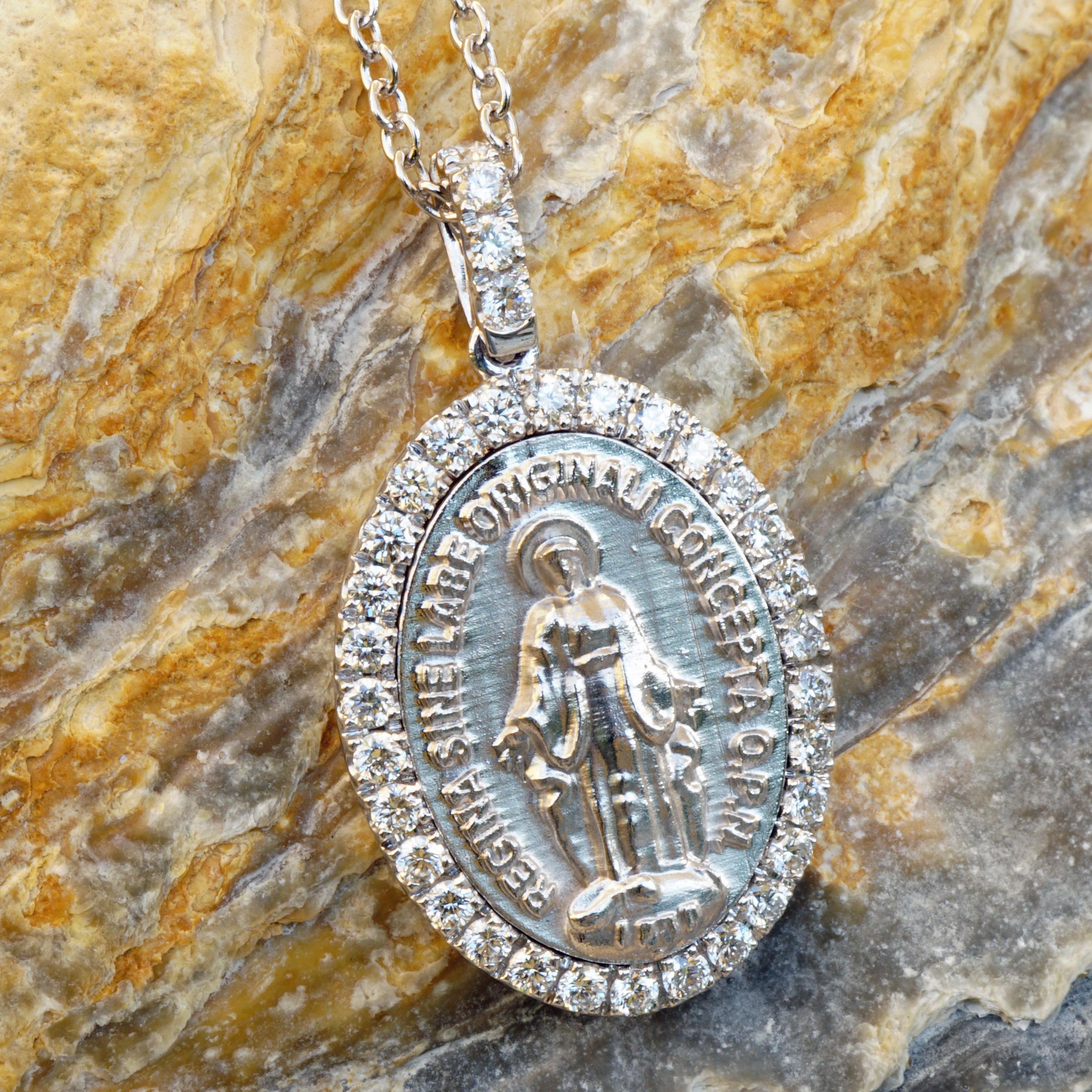 entzückender Madonnen-Anhänger aus Italien, in 750er Weißgold, ovale Form und Anhängeröse besetzt mit Vollschliff-Diamanten, insgesamt ca. 0,21 ct, TW (fine white) / VS (sehr kleine Einschlüsse), ca. 20 x 11 mm groß, präzise gefasst, mit passender