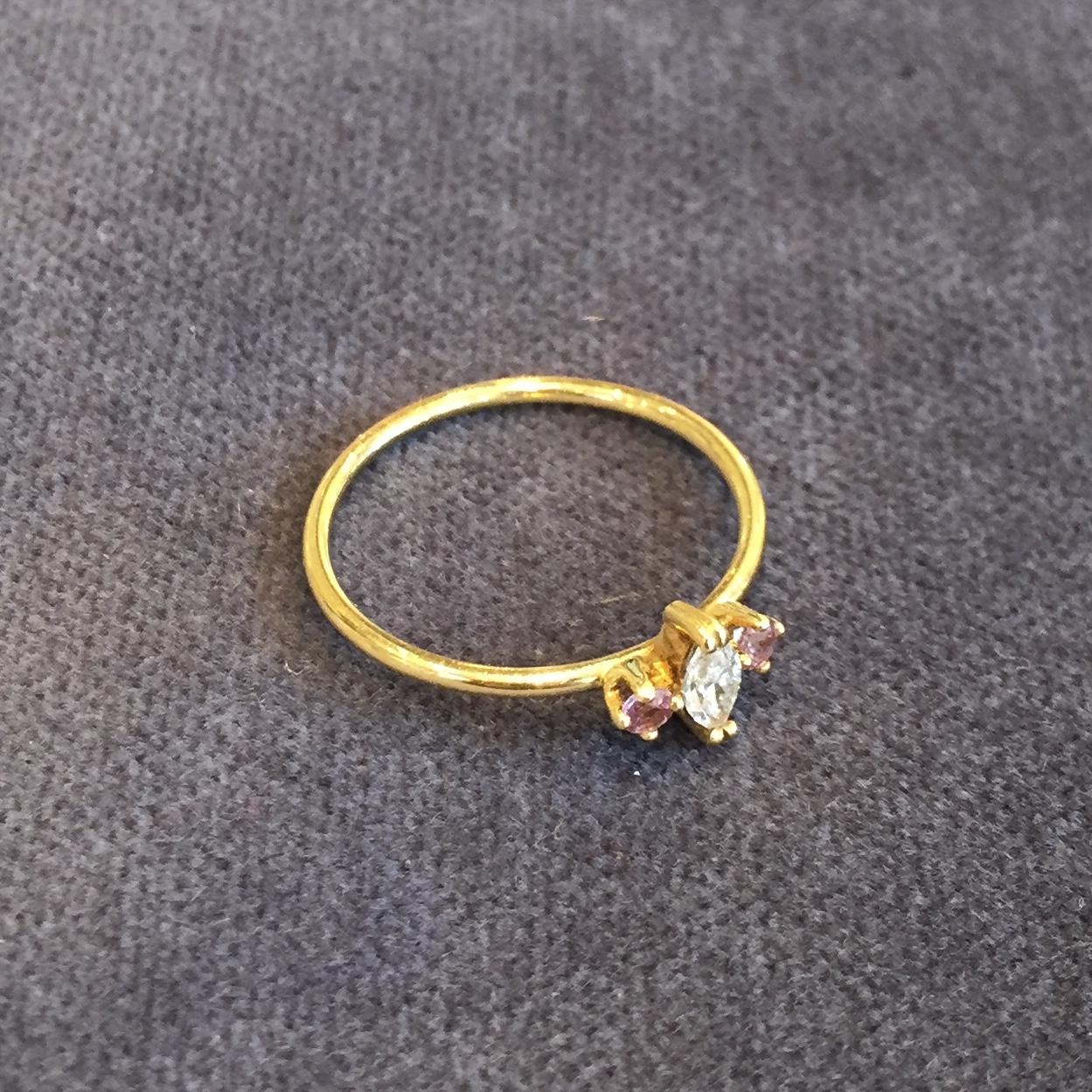 With a marquise cut 0.12carat white diamond claw set with brilliant cut 0.04carat soft pink sapphires either side perfectly balance on a polished 18k yellow gold 1.2mm band. This ring is a UK ring size L, but can be made to order in any size. Please