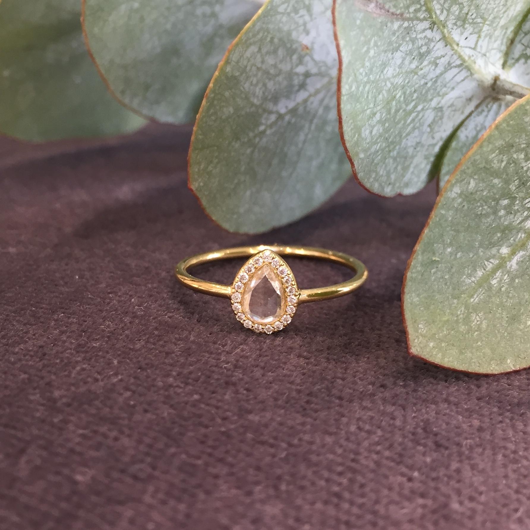 This beautiful one-off piece is a twist on the popular classic round rose cut halo ring. The centre stone is a white pear shaped rose cut diamond with a pave set halo surround of brilliant white diamonds. Set in 18k yellow gold the centre stone is