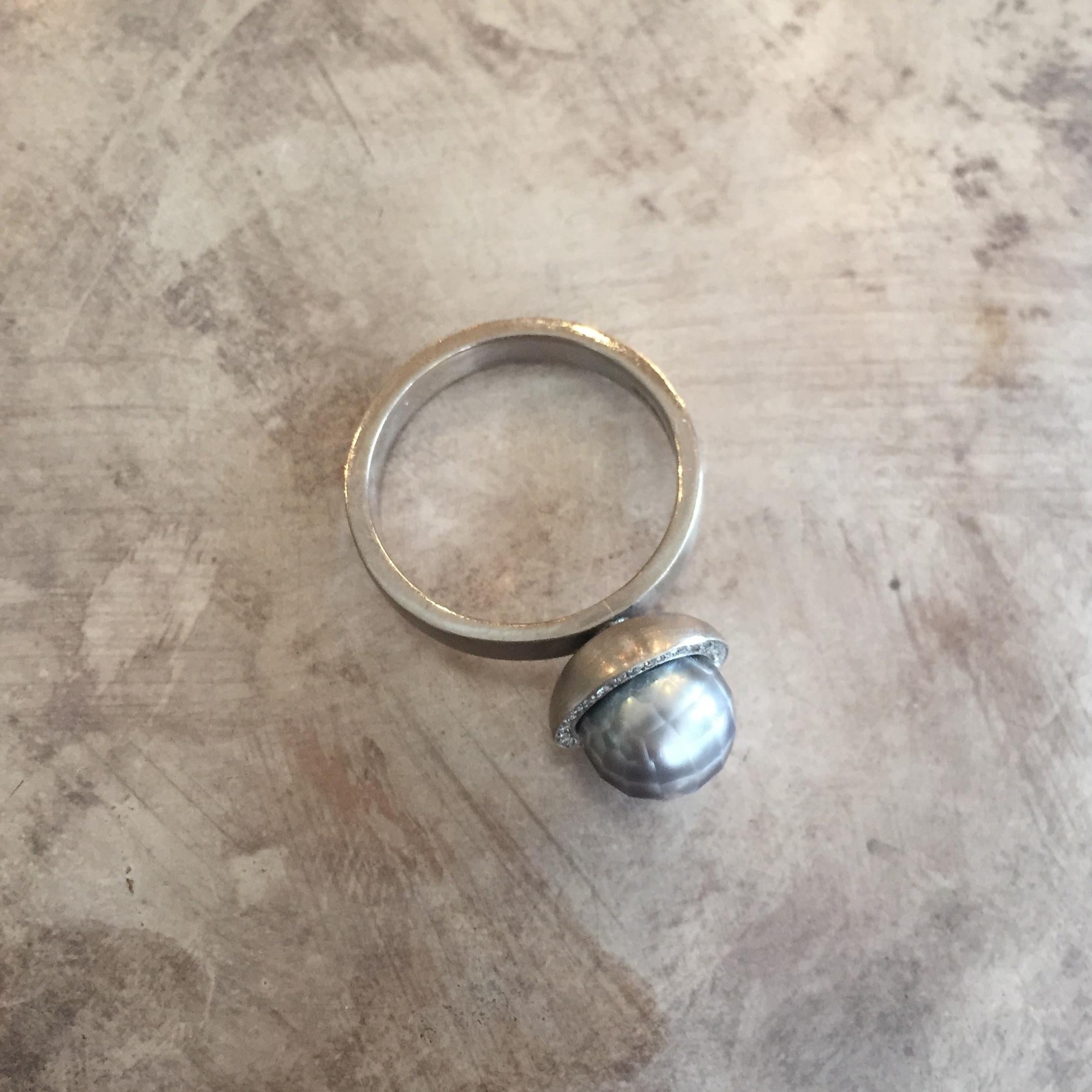 A very unique ring by Sweet Pea, made in 18k white gold. A halo of white diamonds with a total weight of 0.05ct encircles the cool grey faceted pearl. The band is 3mm wide and the pearl is 8mm diameter. This ring is a UK size M, but can be made in