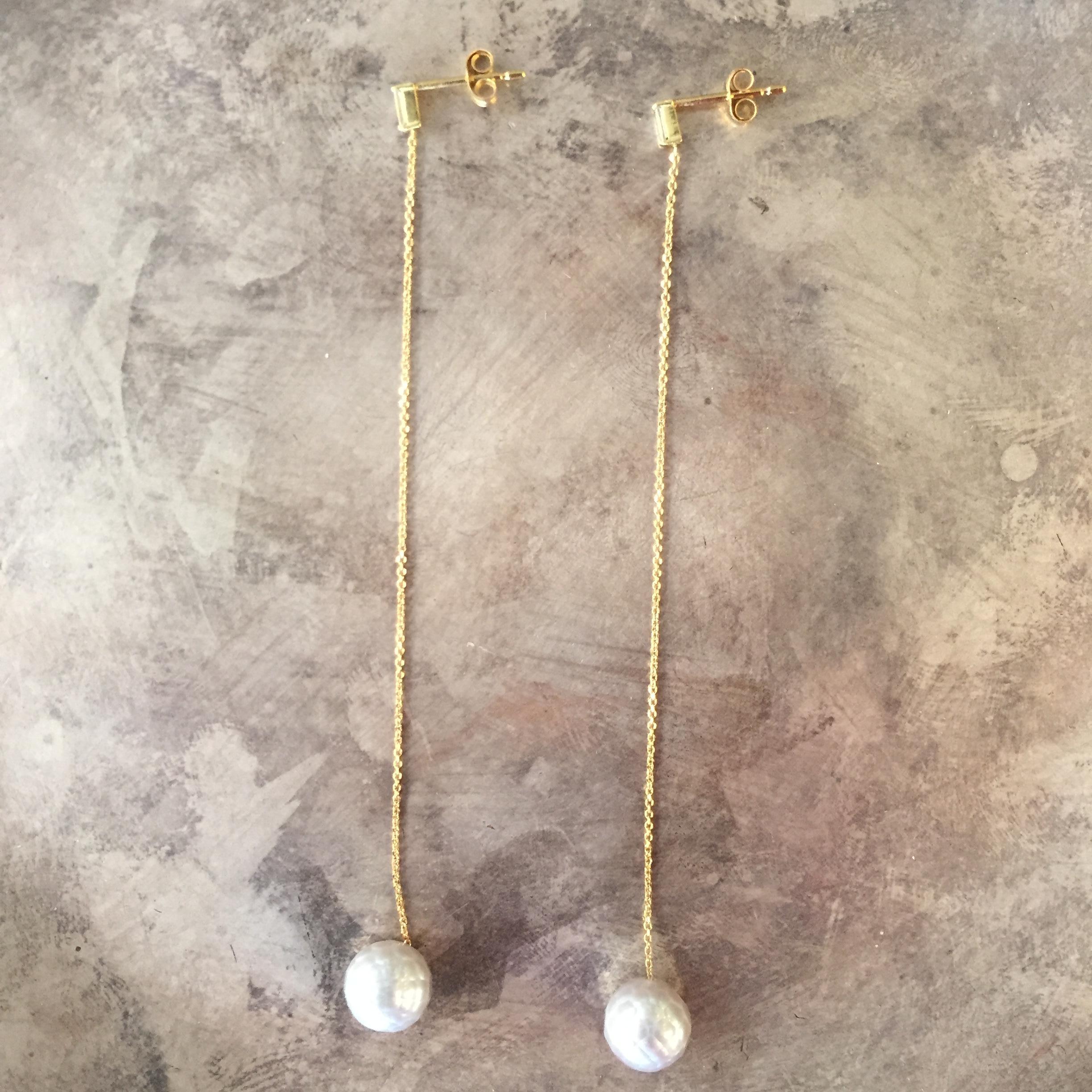 An elegant pair of long drop earrings by Sweet Pea in 18k yellow gold. The total diamond weight is 0.1ct. Total length of each earring is 8.7cm. Glittering fine chain connects the baguette cut diamond studs to the unique faceted grey pearl drops