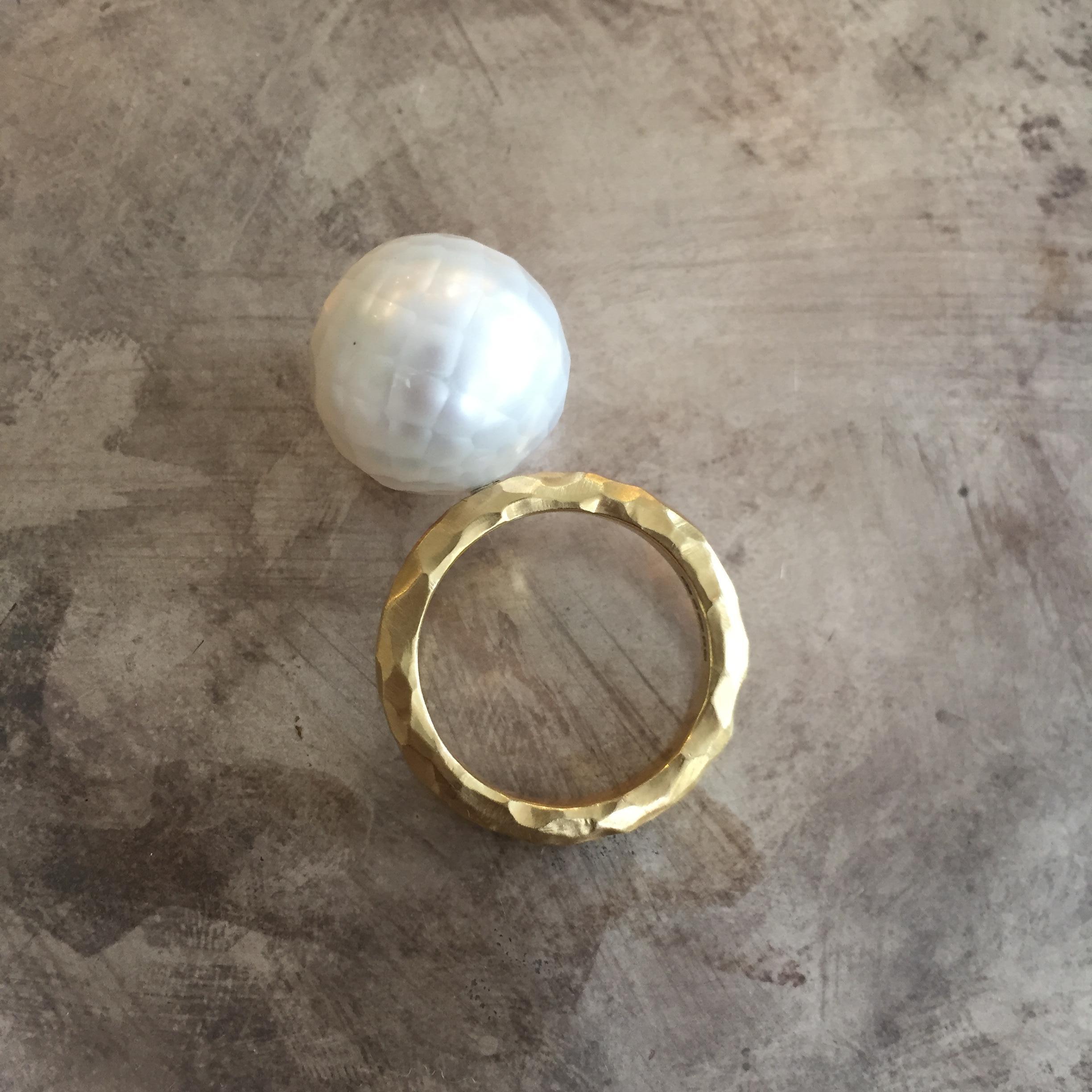 This stunning ring from Sweet Pea features an 18k yellow gold hammered 3mm wide band with a brushed finish. The faceted white South Sea pearl is 15mm in diameter and completely unique. This one-off ring is a UK size M.
