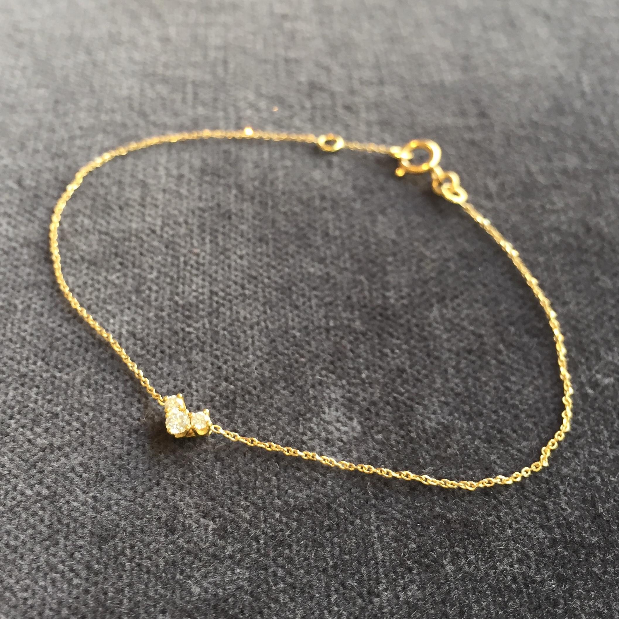This fine chain bracelet is made in 18 karat yellow gold with a pendant of three white diamonds set in a 'V' shape, with a total weight of 0.08 carats. The total length of the bracelet is 17.5cm, but it can be made to any length; please contact us