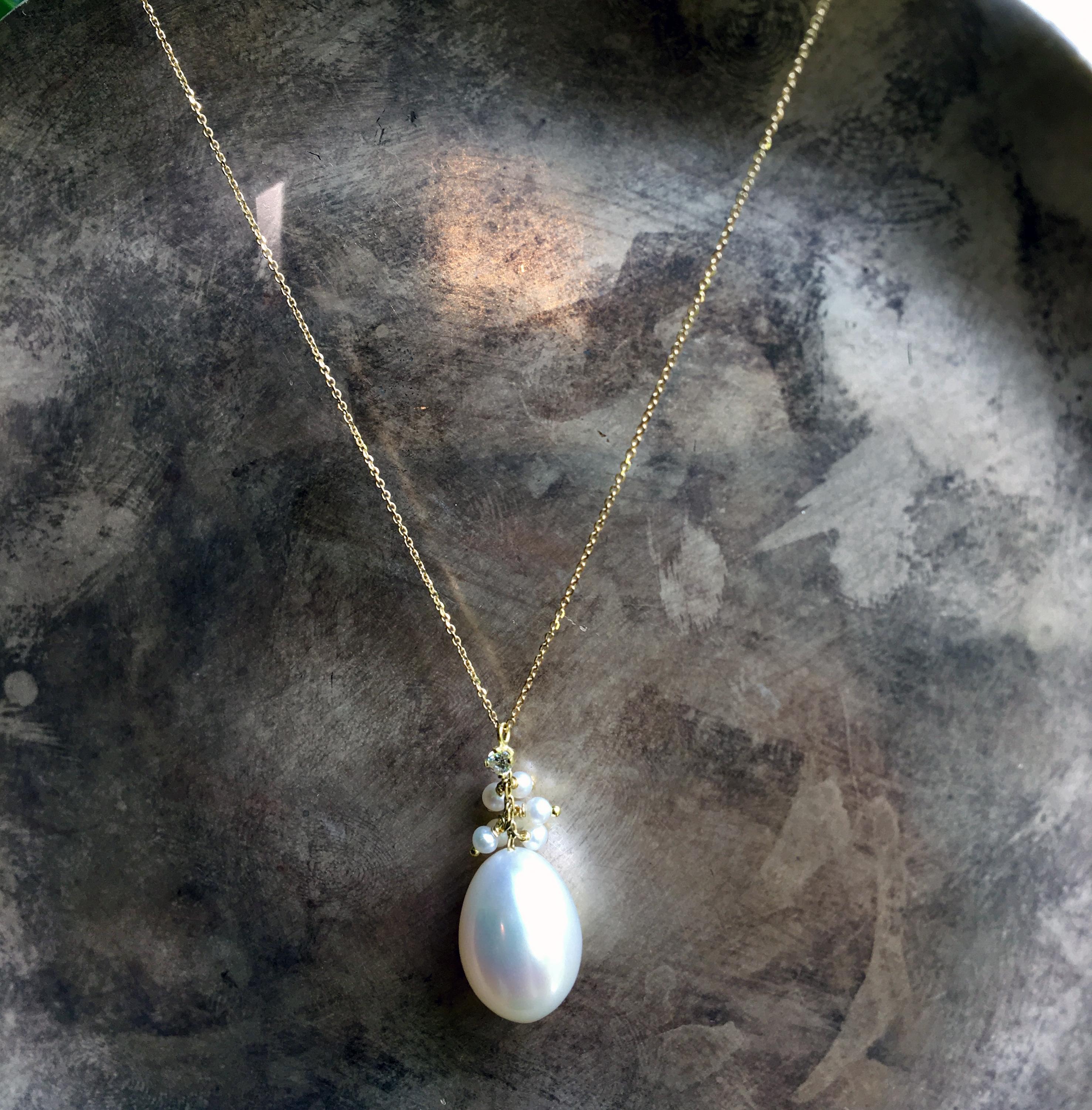 This lovely Sweet Pea necklace is made from 18k yellow gold and features a beautiful large white pearl with a claw set white diamond weighing 0.04ct and a playful cluster of seed pearls. The large pearl is approximately 13x10mm and the small pearls