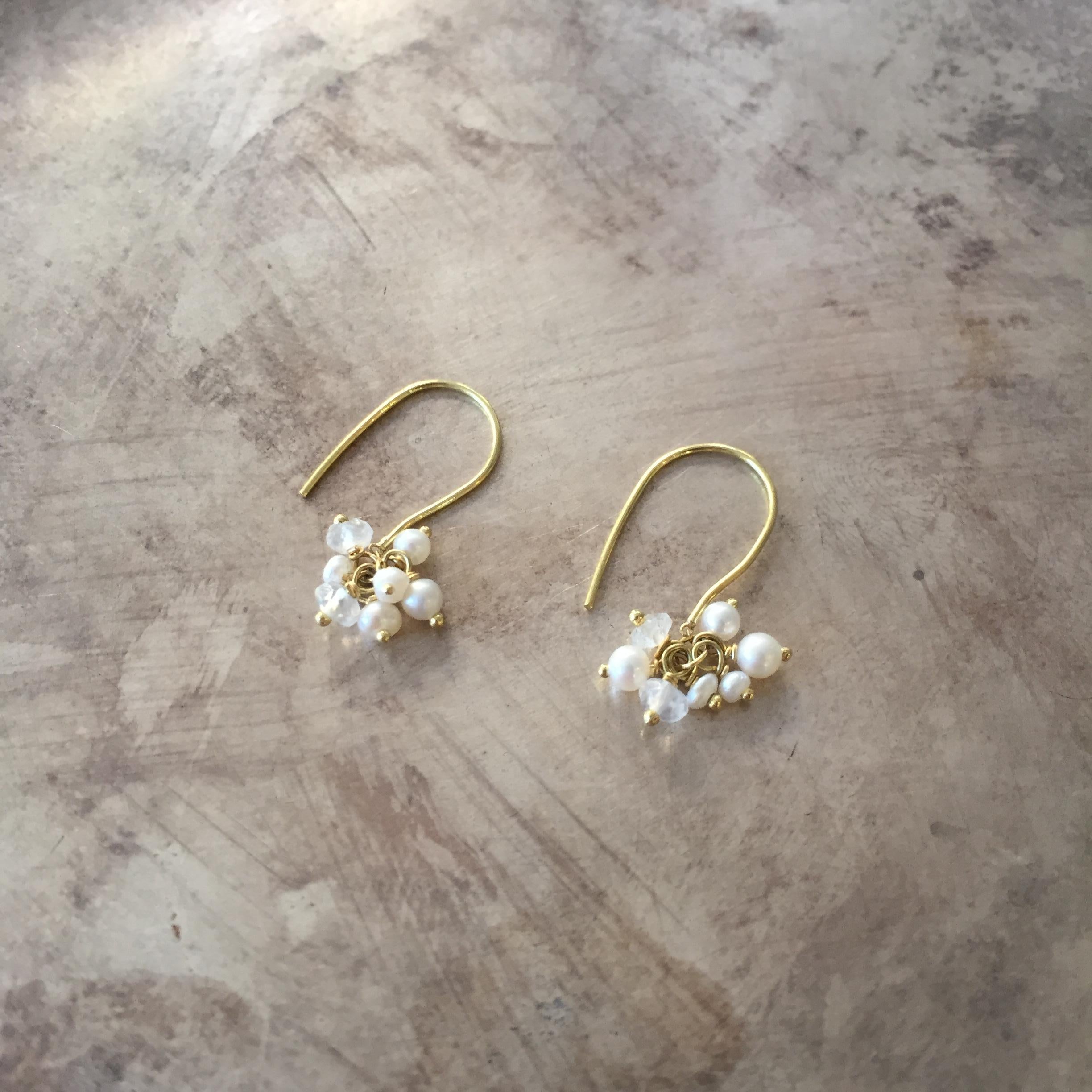 These 18k yellow gold earrings feature a cluster of seed pearls and moonstones, each measuring approximately 2mm-3mm. The total length of the earrings is 18mm. Perfect for all ages and ideal for all occasions, these earrings make the perfect