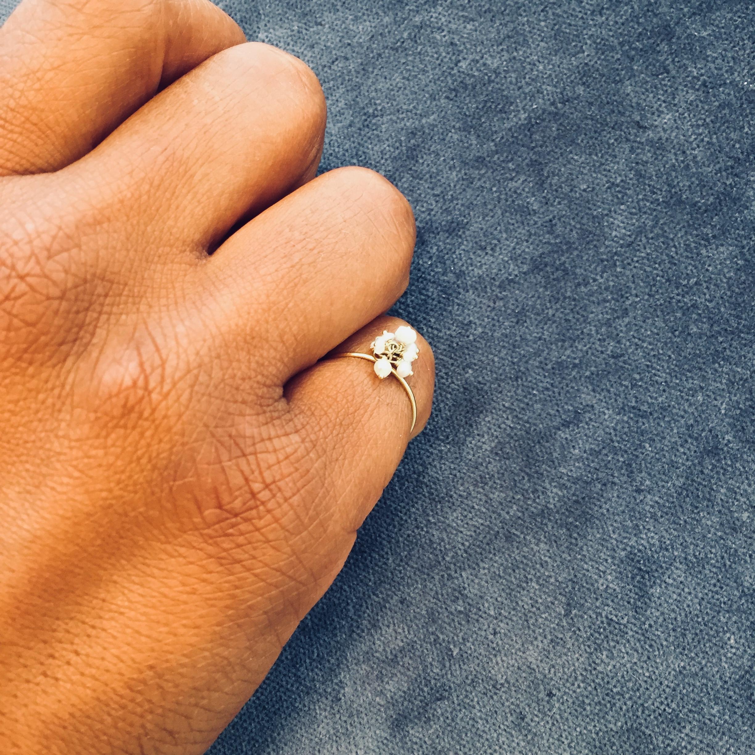 This Sweet Pea 18k yellow gold ring with a cluster of white seed pearls and moonstones is a pearl ring with a twist! The dainty 0.8mm thick band really lets the luminous cluster take center stage as it moves. Handmade in the Sweet Pea London