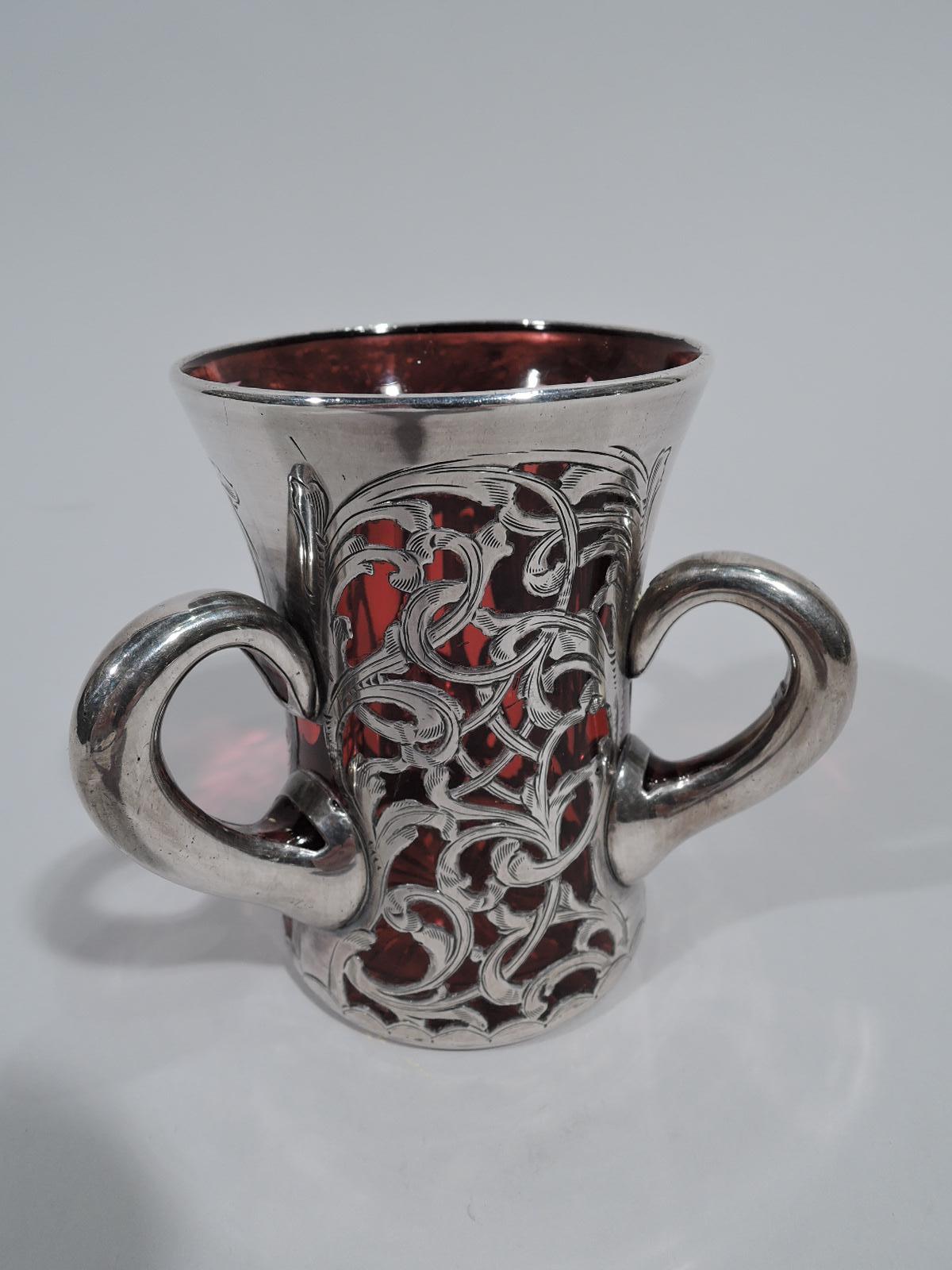 Turn-of-the-century Art Nouveau glass vase with engraved silver overlay. Gently flared cylinder with dense and entwined leafing scrolls. Asymmetrical scrolled cartouche (vacant). Three collared scroll handles. Cut-to-clear star on underside. Glass