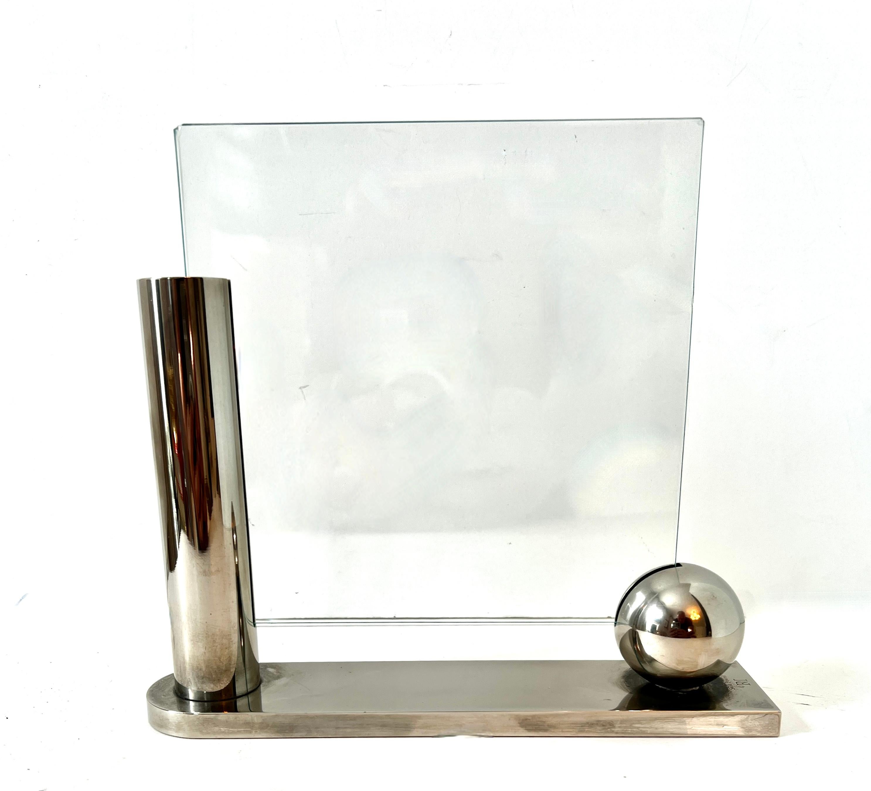 A stunning example of Richard Meiers work with Swid Powell.   The sliver plated picture frame is a modern piece with a sphere and cylinder which house two pieces of glass floating.  

A compliment to any desk, console or bedside and a perfect