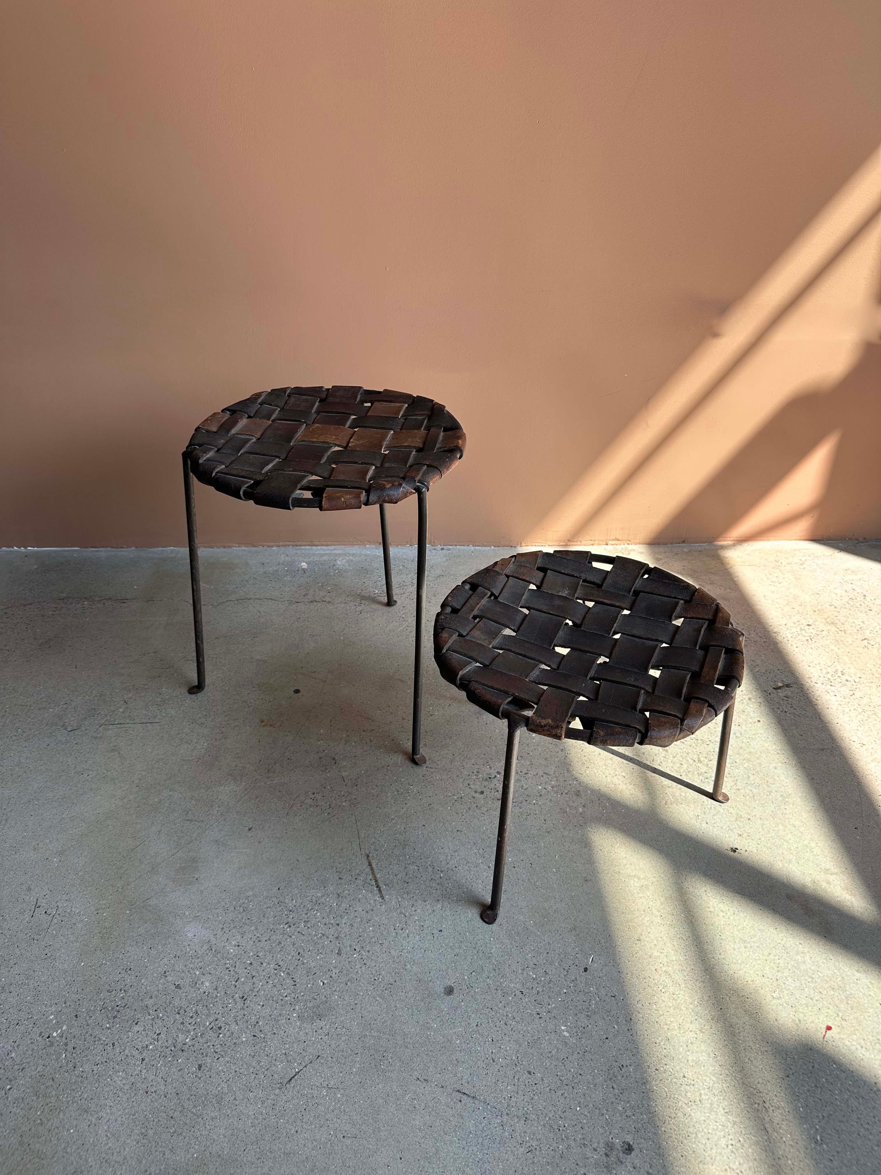 A beautifully patinated pair of mid-century stools by Swift & Monell, crafted in the USA circa 1950s. These sculptural pieces feature round tops made from richly aged, hand-woven leather straps. Versatile enough to serve as side tables, plant