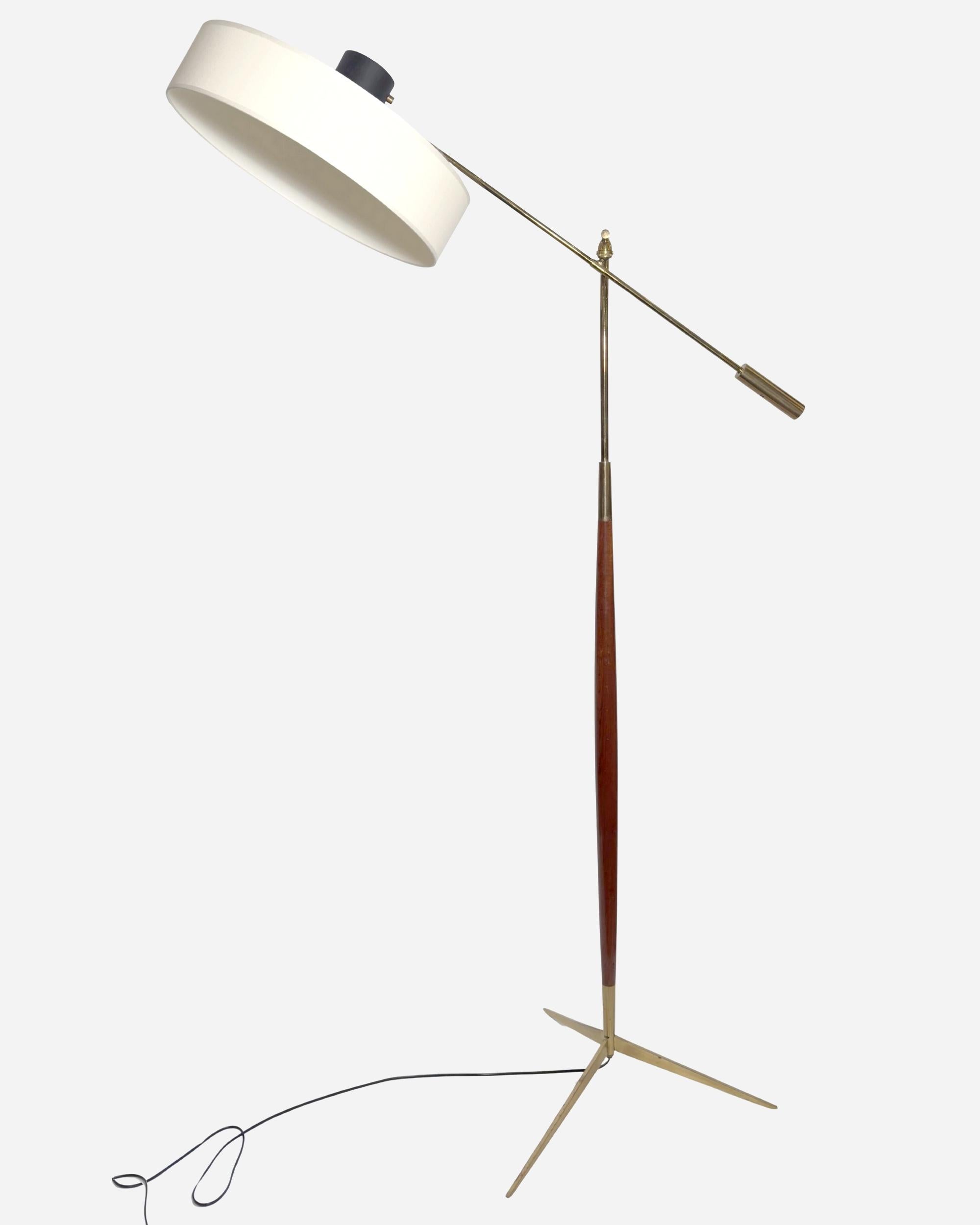 Lampada da terra a pendolo. Base a treppiede in ottone dorato da cui si erge un'asta in legno che ospita un braccio articolato rifinito con un contrappeso, anch'esso in ottone dorato. Questo braccio sostiene un grande riflettore. Paralume recente,