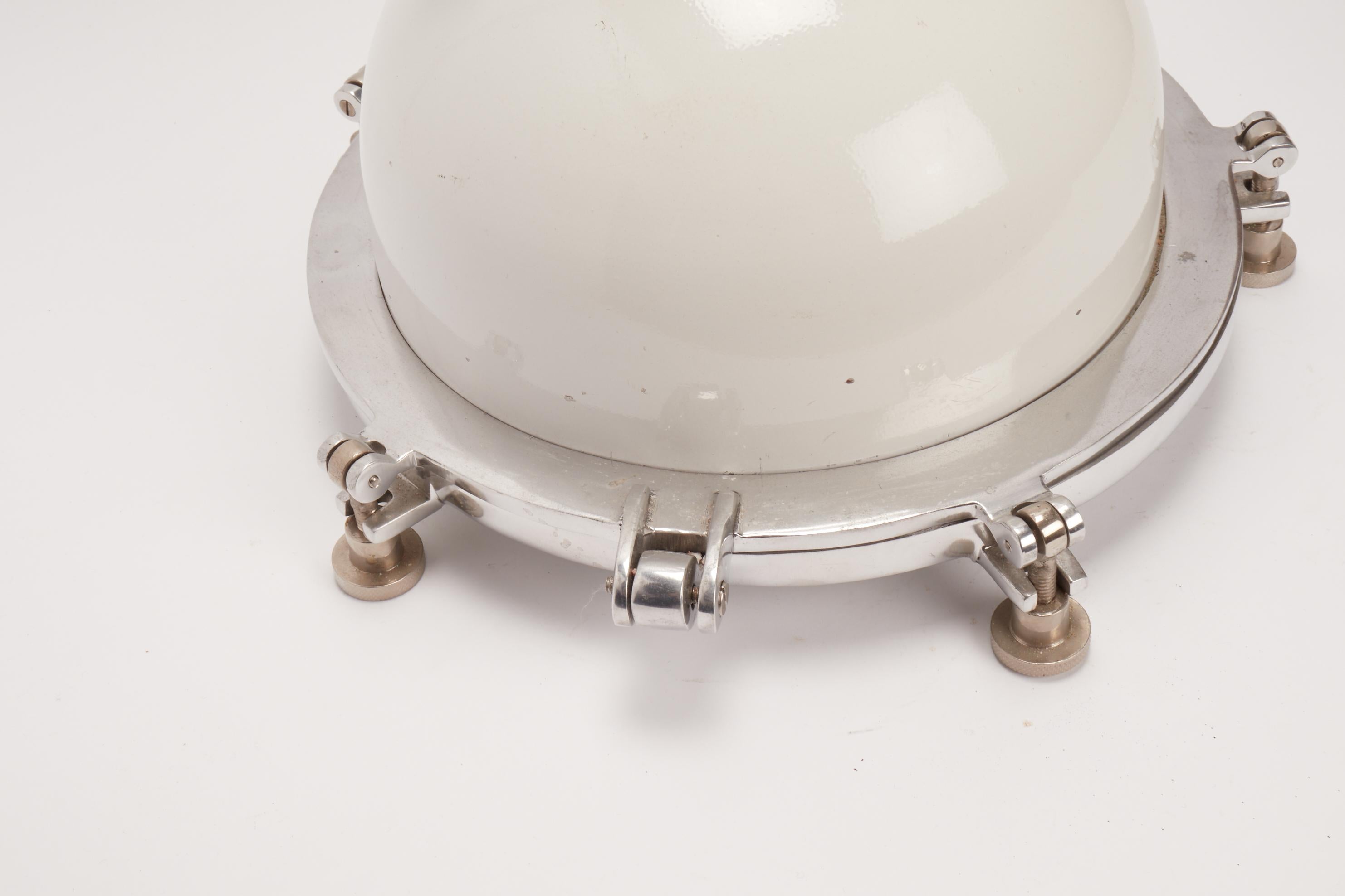 Swinging metal white enameled boat lamp, with an aluminum and glass to protect the bulb, USA, circa 1930.