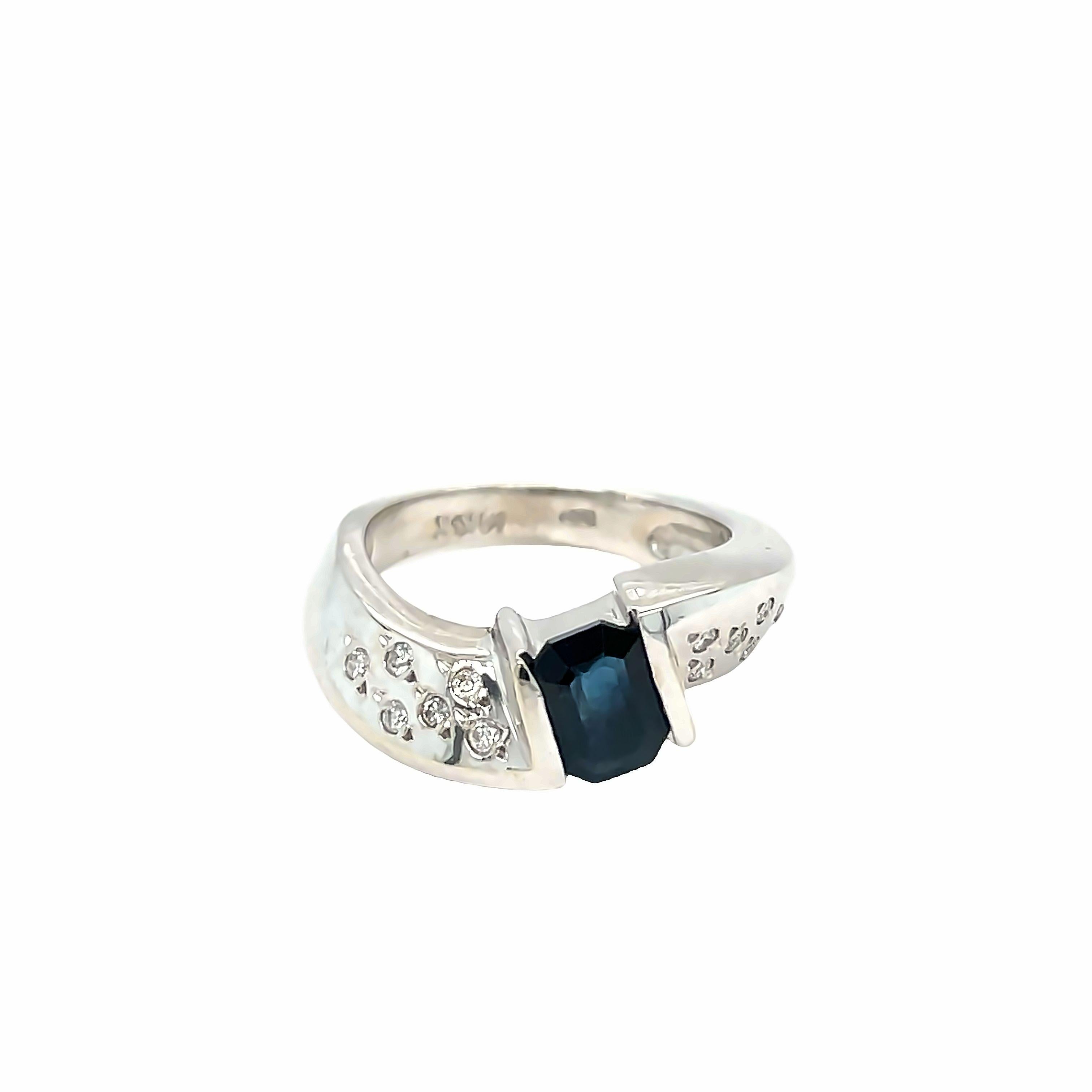 Elegant and contemporary, this 14K White Gold Sapphire Diamond Ring features a stunning radiant cut Sapphire weighing approximately 0.90 carat. Sapphire is beautifully showcased in a half-bezel setting, complemented by a dome setting adorned with