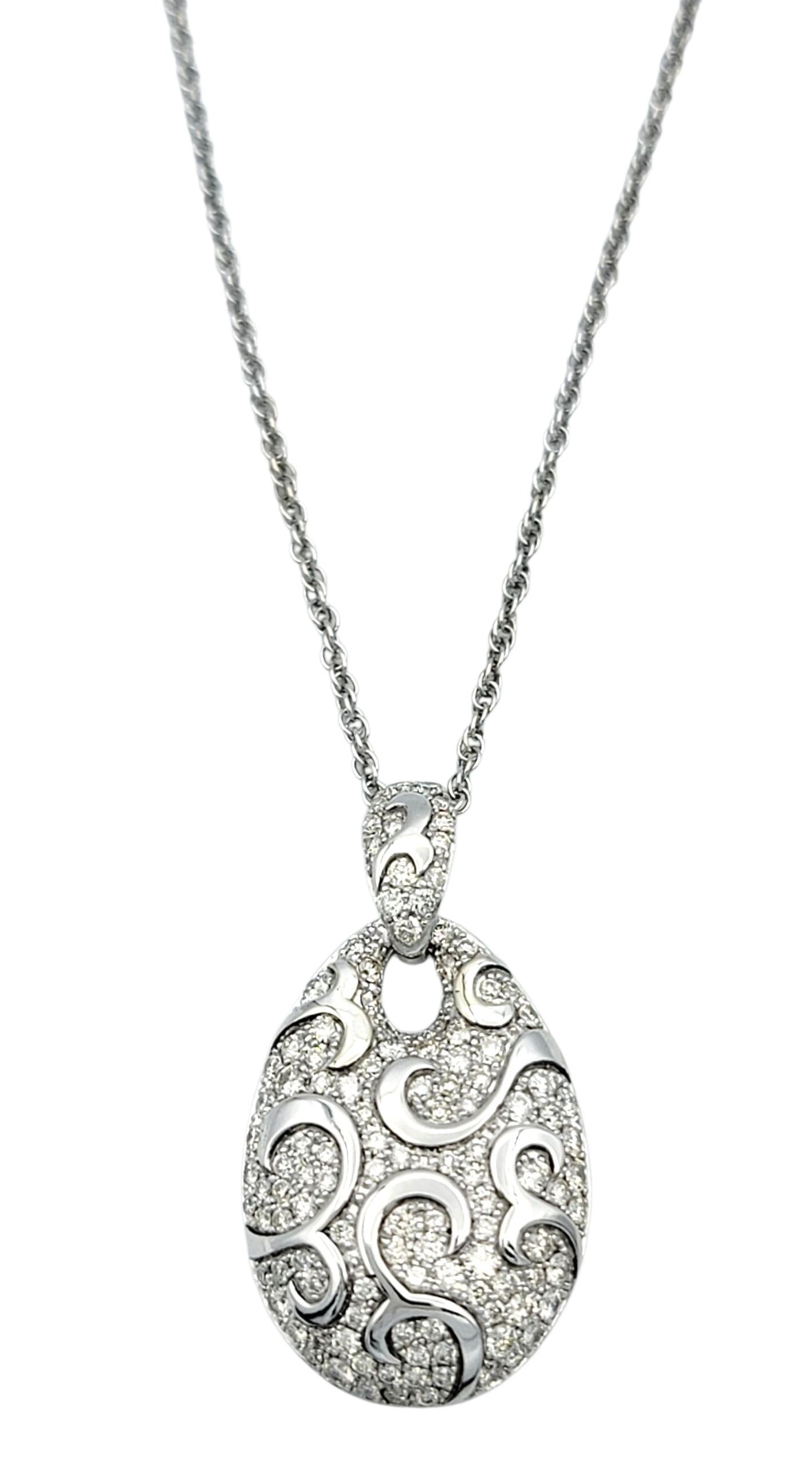 Diese elegante Halskette mit Anhänger ist aus 14 Karat Weißgold gefertigt und in Tropfenform mit filigranen Details gestaltet. Der Anhänger funkelt in einer Pavé-Fassung aus Brillanten, die so angeordnet sind, dass sie das fließende Rankenwerk
