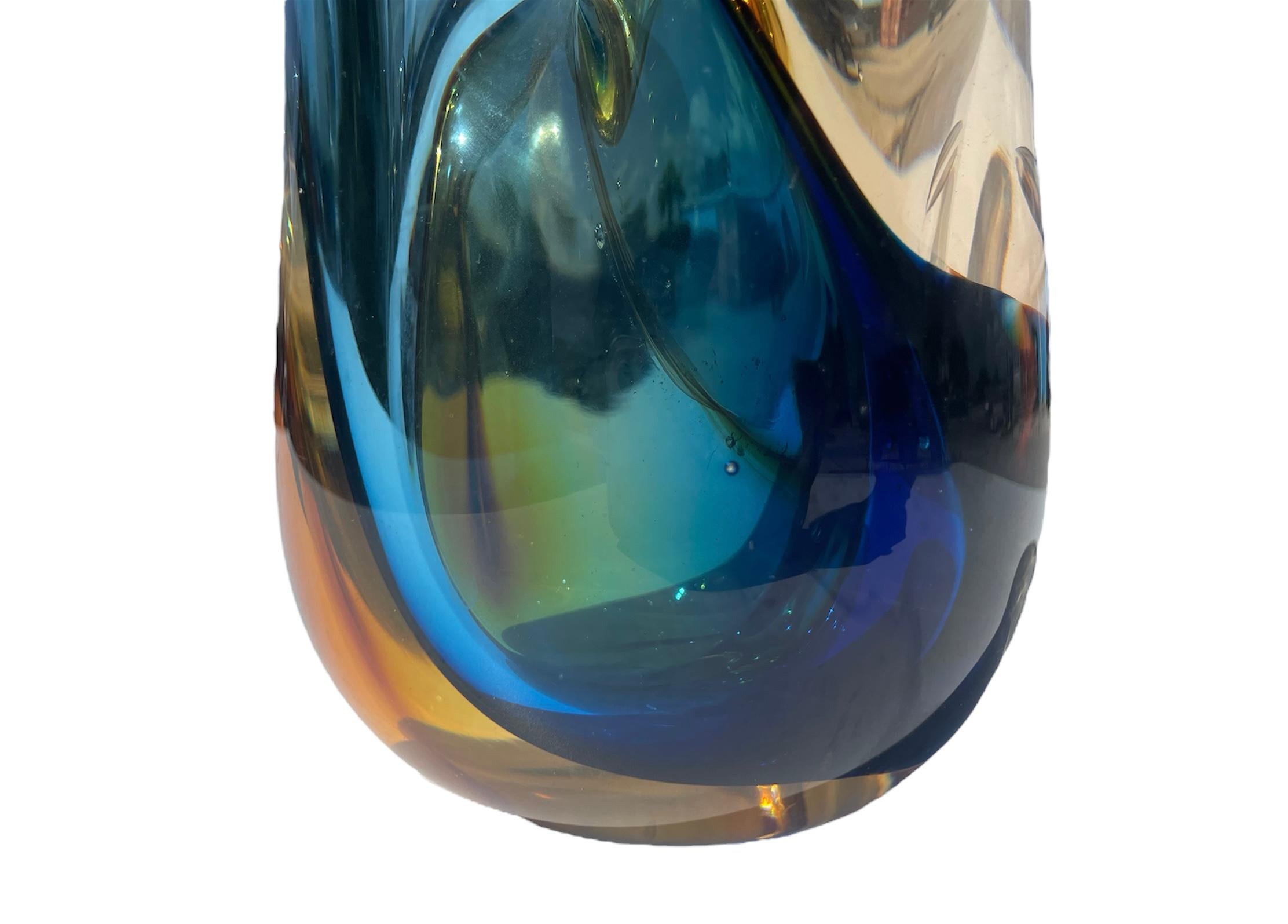 Absolutely stunning piece of art glass, heavy in weight, has the feel of a large paper weight when you pick it up. The colors in the glass are very vivid with various shades of blues and yellows( seen in certain lights and burnt rusty orange. The