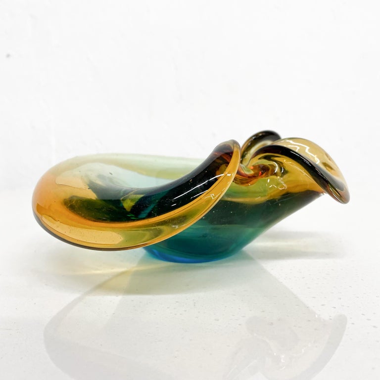 Glass Bowl Ashtray
Swirling Green and Amber Curled Murano Sommerso Art Glass clam shaped ashtray dish bowl style of Archimede Seguso Italy
Measures: 7 X 7 D x 2.63 H inches
Unmarked.
Original Unrestored preowned good vintage condition.
Refer to