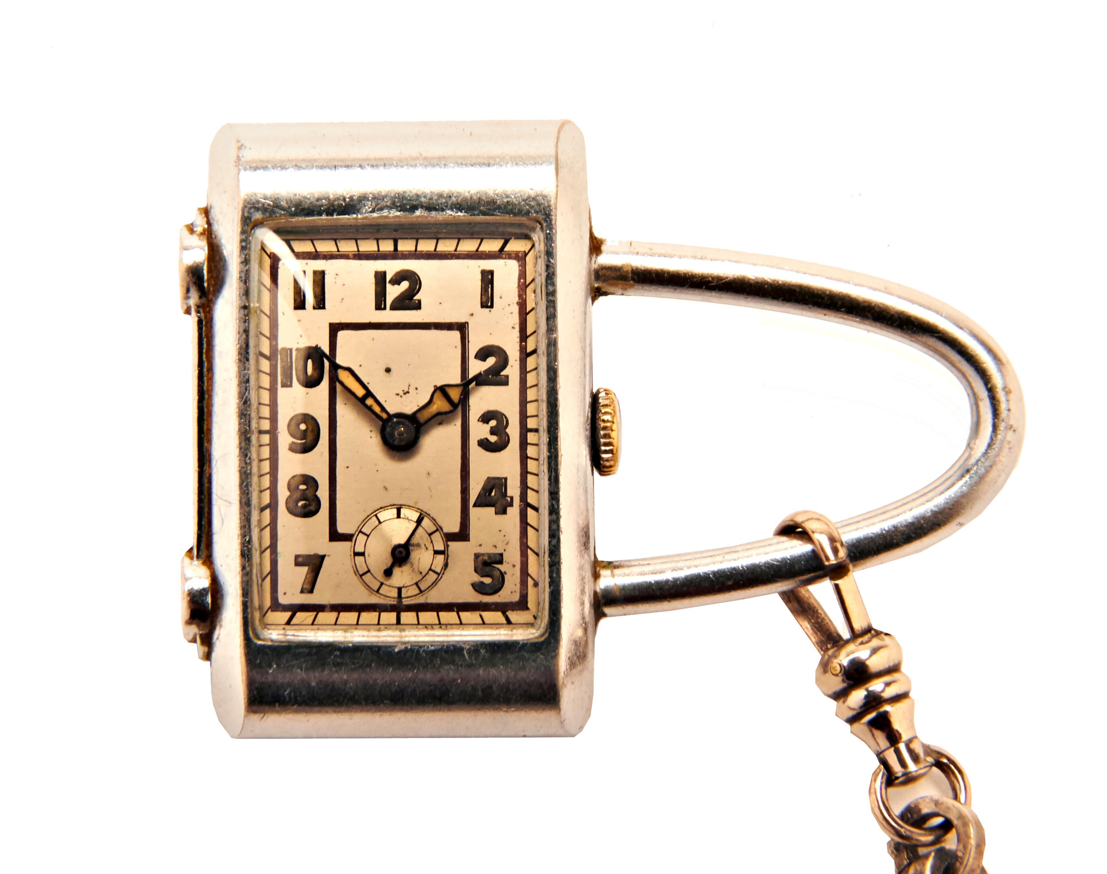 This beautifully designed Art Deco or Machine Age purse watch is executed in polished steel and is complete with its original ball and chevron articulated fob. The watch itself is padlocked shaped and features an Art Deco styled face and hands with