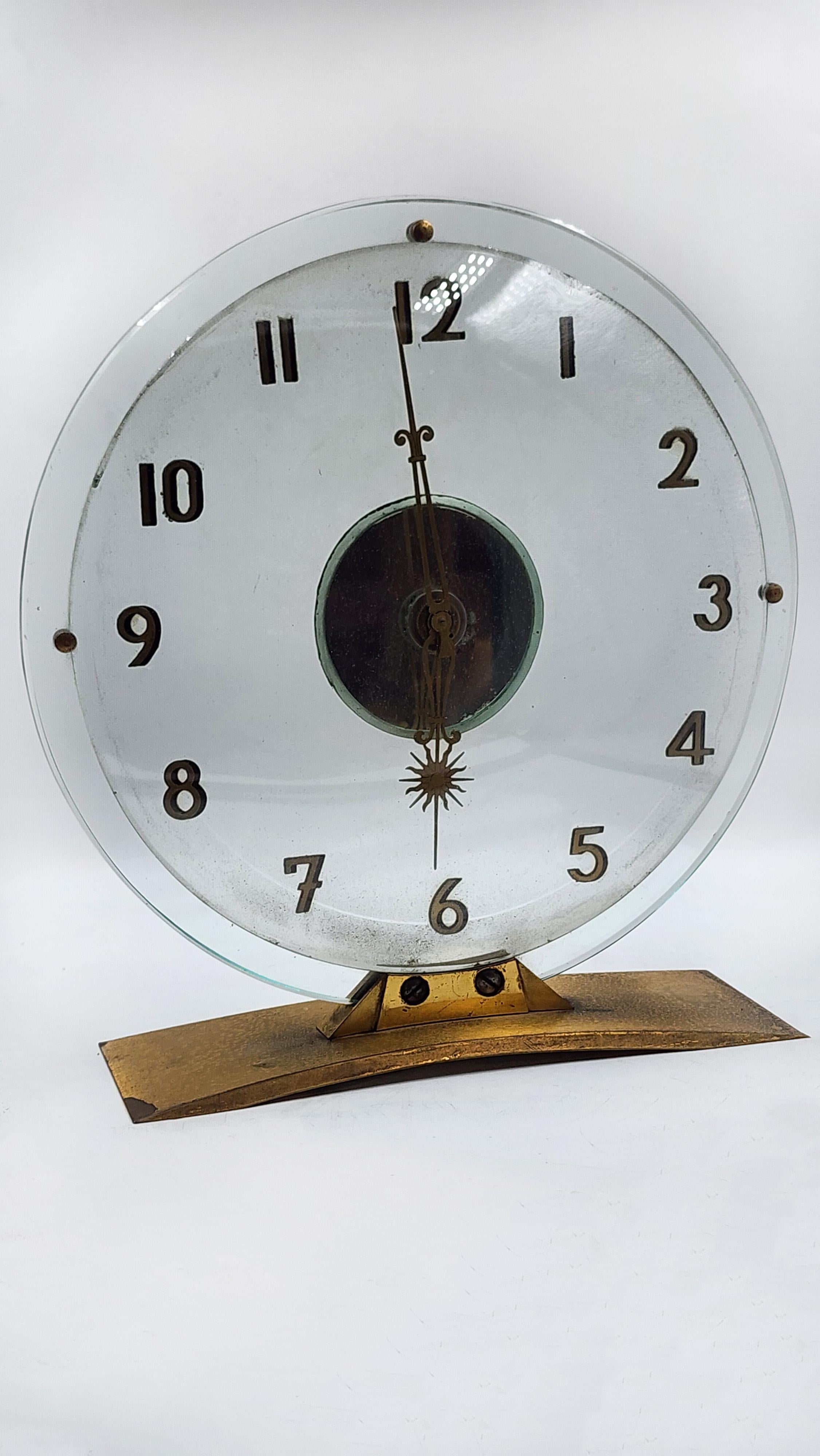 Swiss Art Deco Mantel Clock, 1930
This Art Deco mantel clock features a circular, clear glass dial that allows for an unobstructed view. The Arabic numerals and hour markers are silkscreened directly onto the glass. The hands, along with the