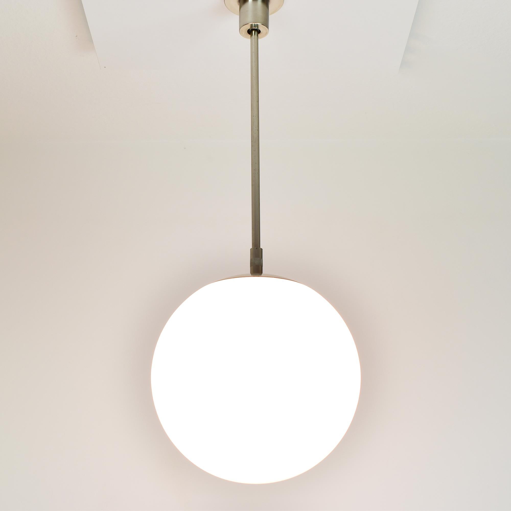 This exquisite Swiss design pendant lamp from the Bauhaus era, crafted by BAG Turgi features a sleek metal mounting complemented by a smooth, spherical glass shade, creating a harmonious balance of form and function. The design allows an optimal