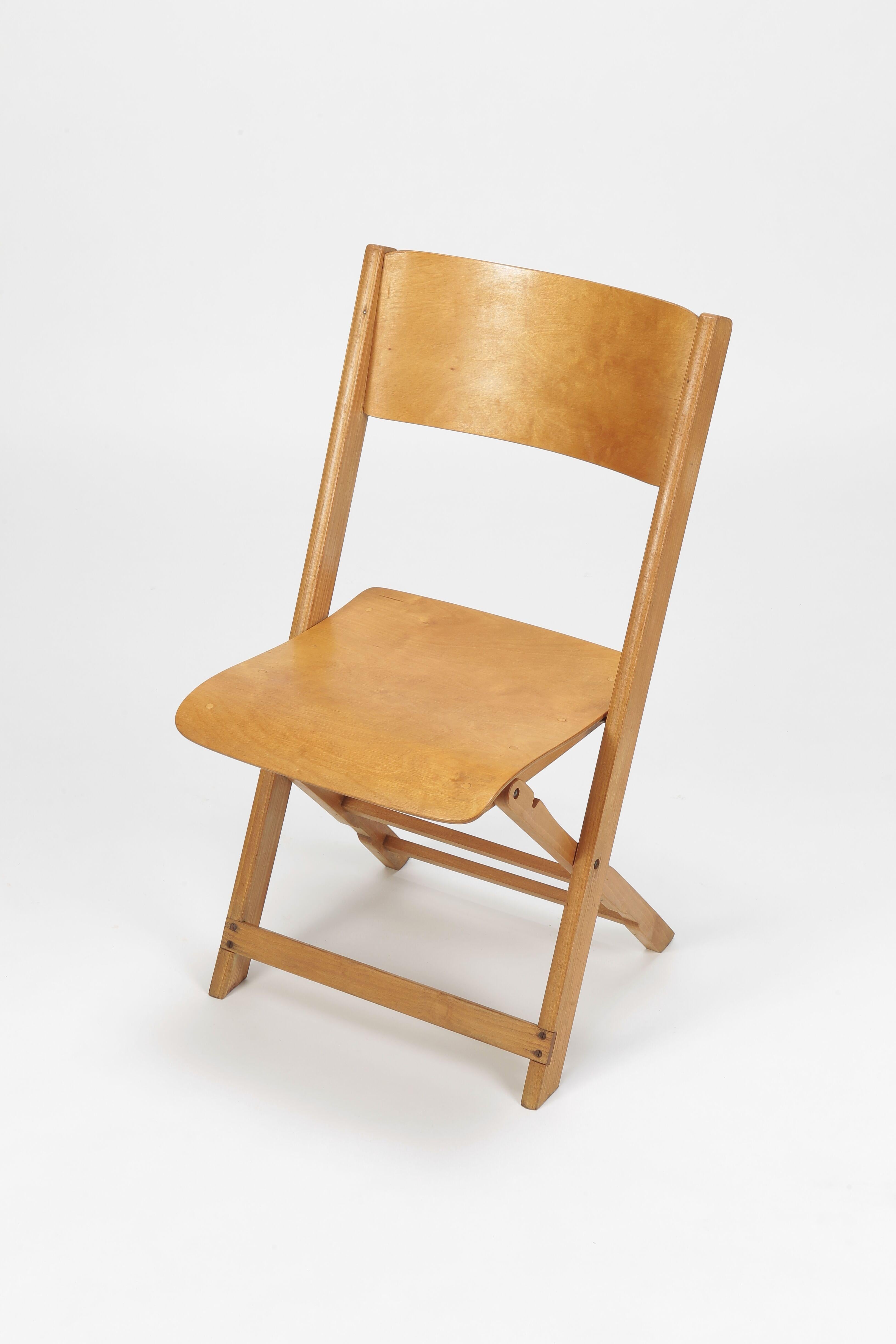 Charming Swiss birchwood folding chair from the 1940s, made by Wohnbedarf. The chair gleams in goldish yellow and its high quality finish is particularly evident on the curved seat and backrest which are made of birchwood. The frame is made of