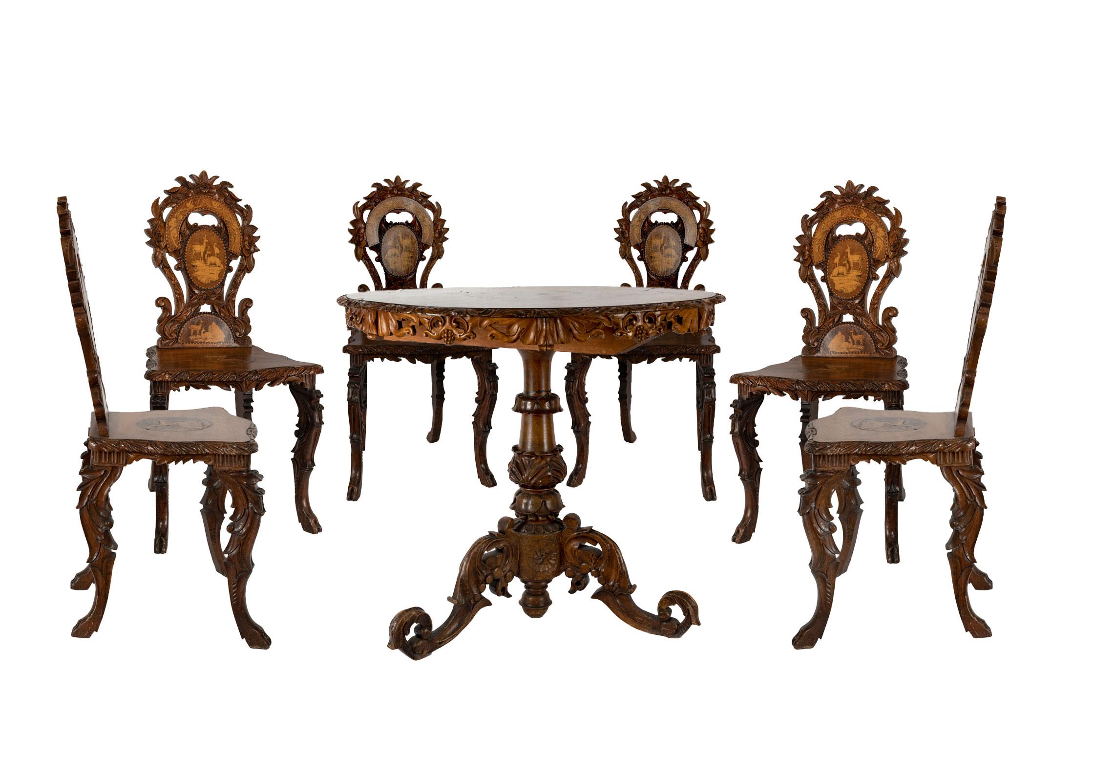 An ornately carved inlaid Swiss black forest table and chair set. The round tilt-table is inlaid with a centre medallion depicting a hunting scene and is surrounded by eight smaller inlaid goat-scene oval medallions, with a piered foliate apron, the
