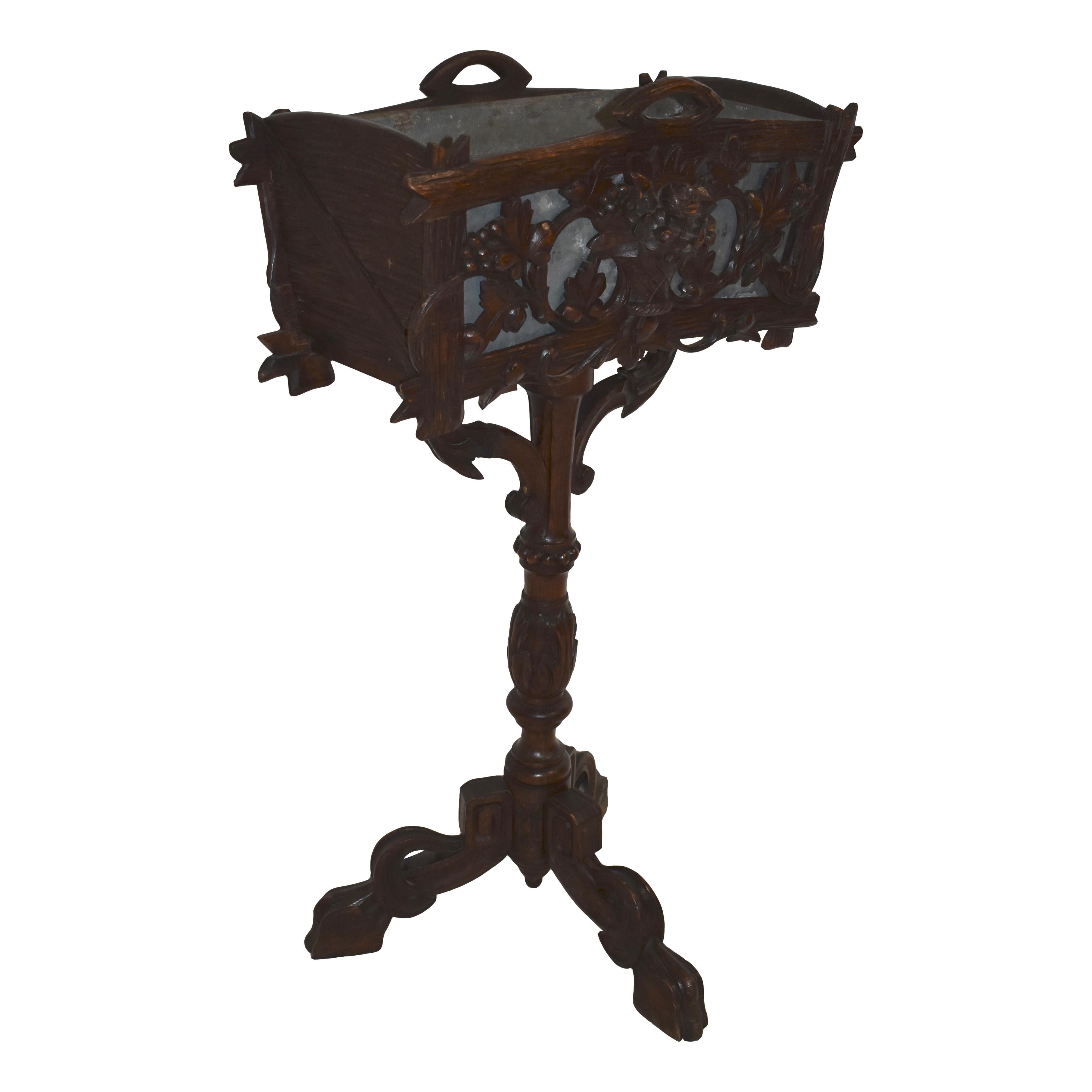 Graceful and elegant, this beautiful wooden planter box features a pierced front carving of a floral basket flanked by scrolled grape vines. The back and sides of the box are carved to look like rough wooden boards. Raised on a turned and carved