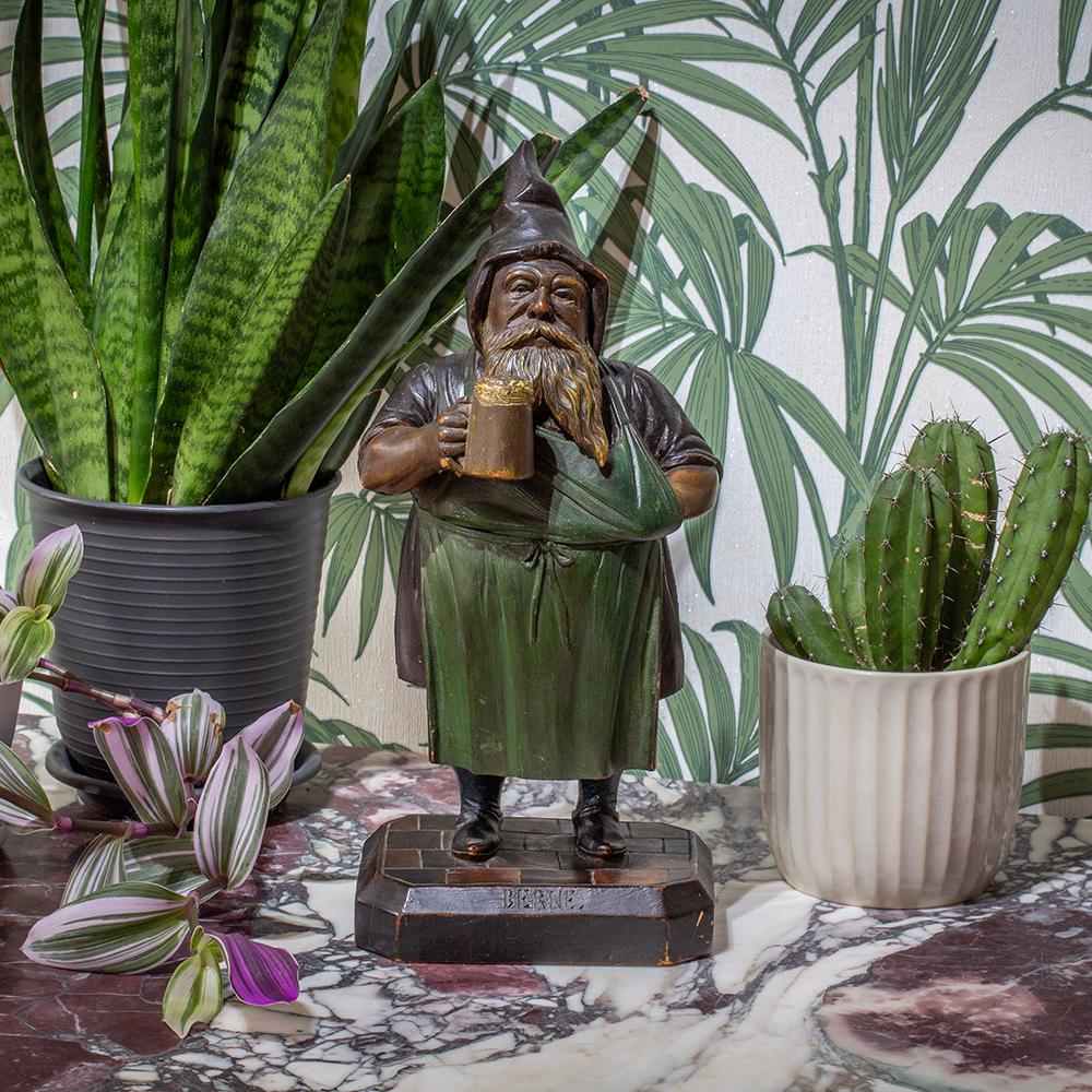 The Gnome stands proud wearing a green apron, hooded top with a large stein in his right hand and his left hand resting in his pocket.  The jar is hinged at waistline of the Gnome allowing access to the tobacco store within the hollowed out body.
