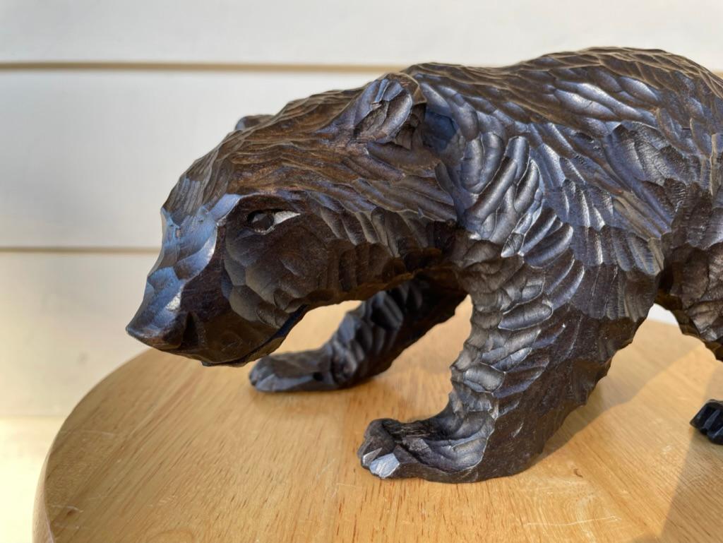 Une magnifique sculpture de la Forêt Noire représentant un ours en train de marcher, sculptée dans un style à la fois réaliste et expressionniste. L'ours montré marche en avant sur ses quatre pattes, le nez au sol. Le rendu réussi de la posture de