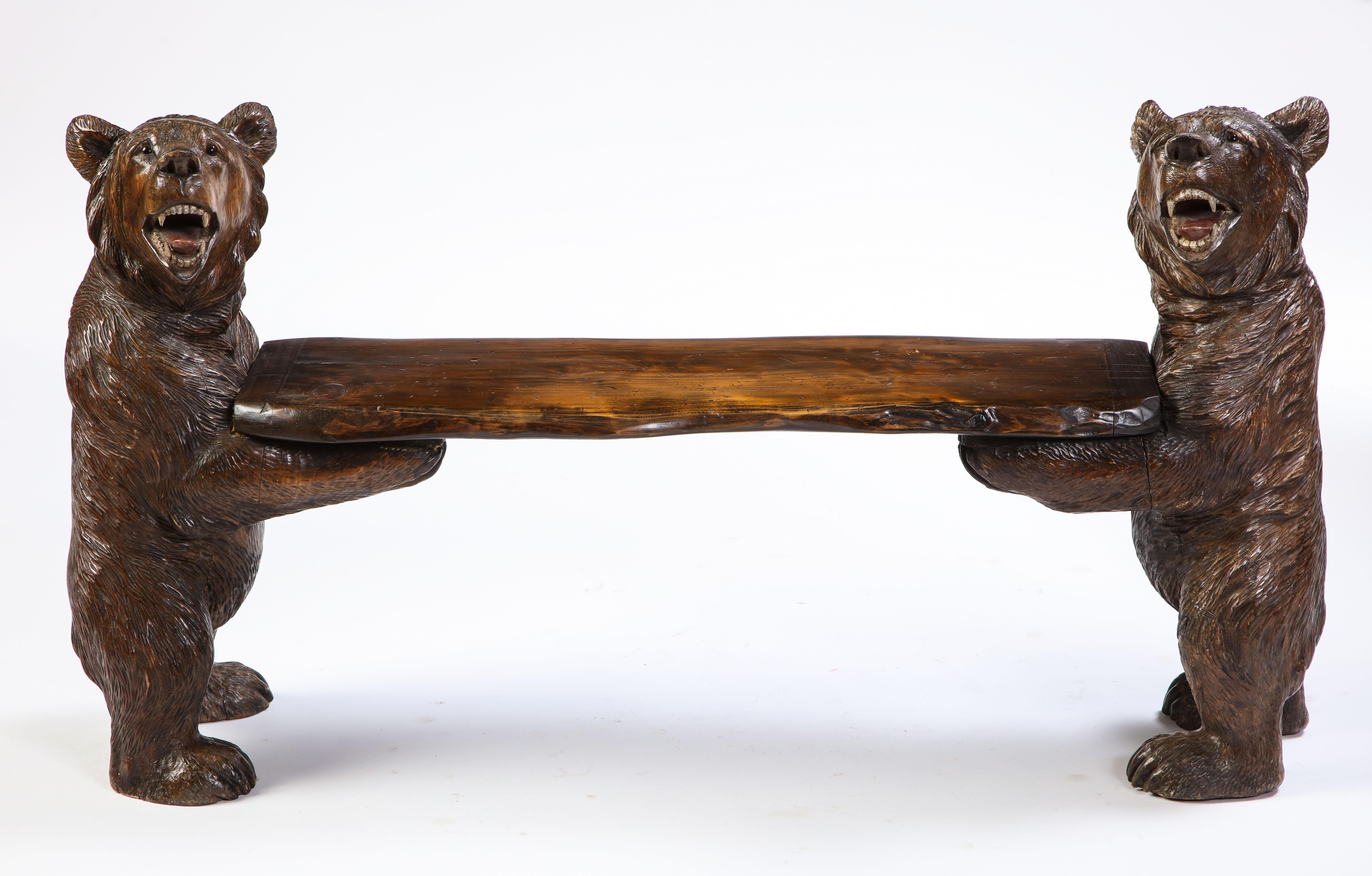 Two expressively carved wooden bears form the legs supporting a plain seat rail in this 20th century Swiss 'Black Forest' small wood bench. The seat rail is composed of a polished and varnished live-edge form plank. This simple Alpine form has