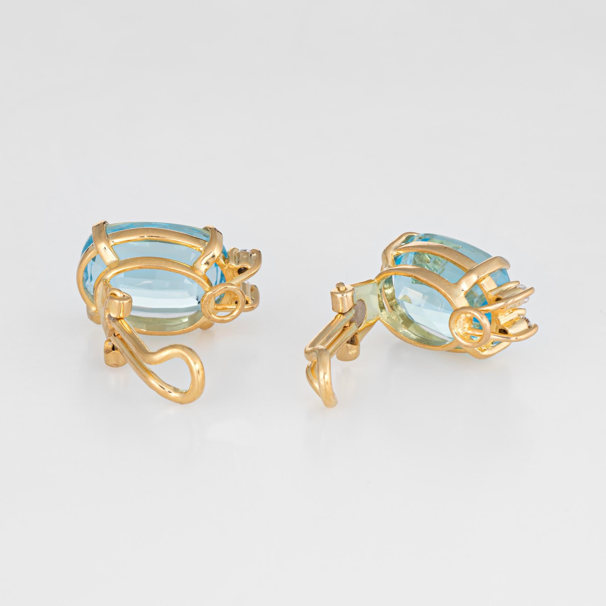Elegant pair of blue topaz & diamond earrings crafted in 18k yellow gold. 

Oval cut faceted blue topaz measuring 13mm x 10mm (estimated at 5 carats each - 10 carats total estimated weight), accented with four estimated at 0.01 carat diamonds. The