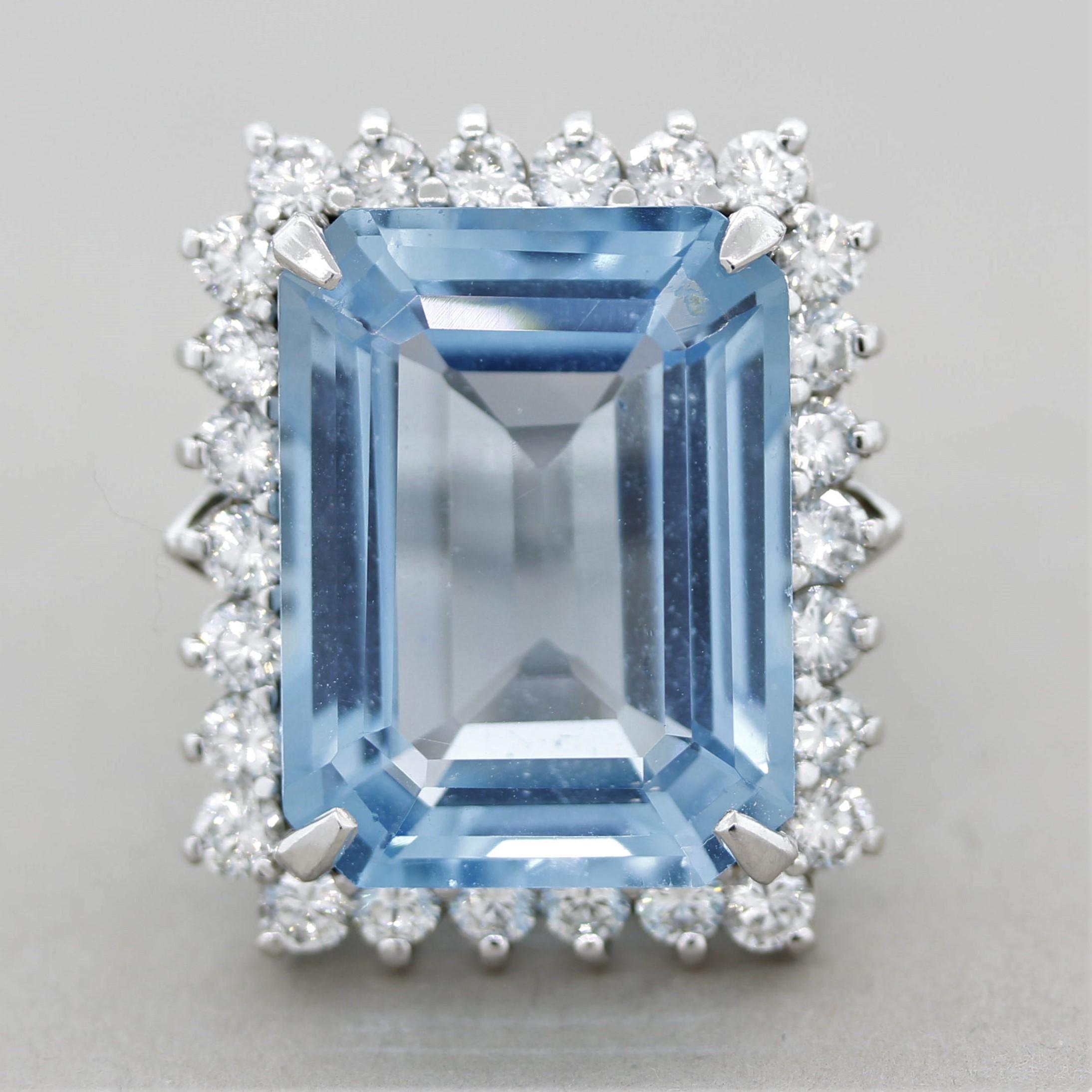 A large and luxurious blue topaz ring! The sky-blue colored gem weighs 25.69 carats and has a precise emerald-cut and rectangular shape that is free of any eye-visible inclusions. It is accented by 1.99 carats of round brilliant-cut diamonds which