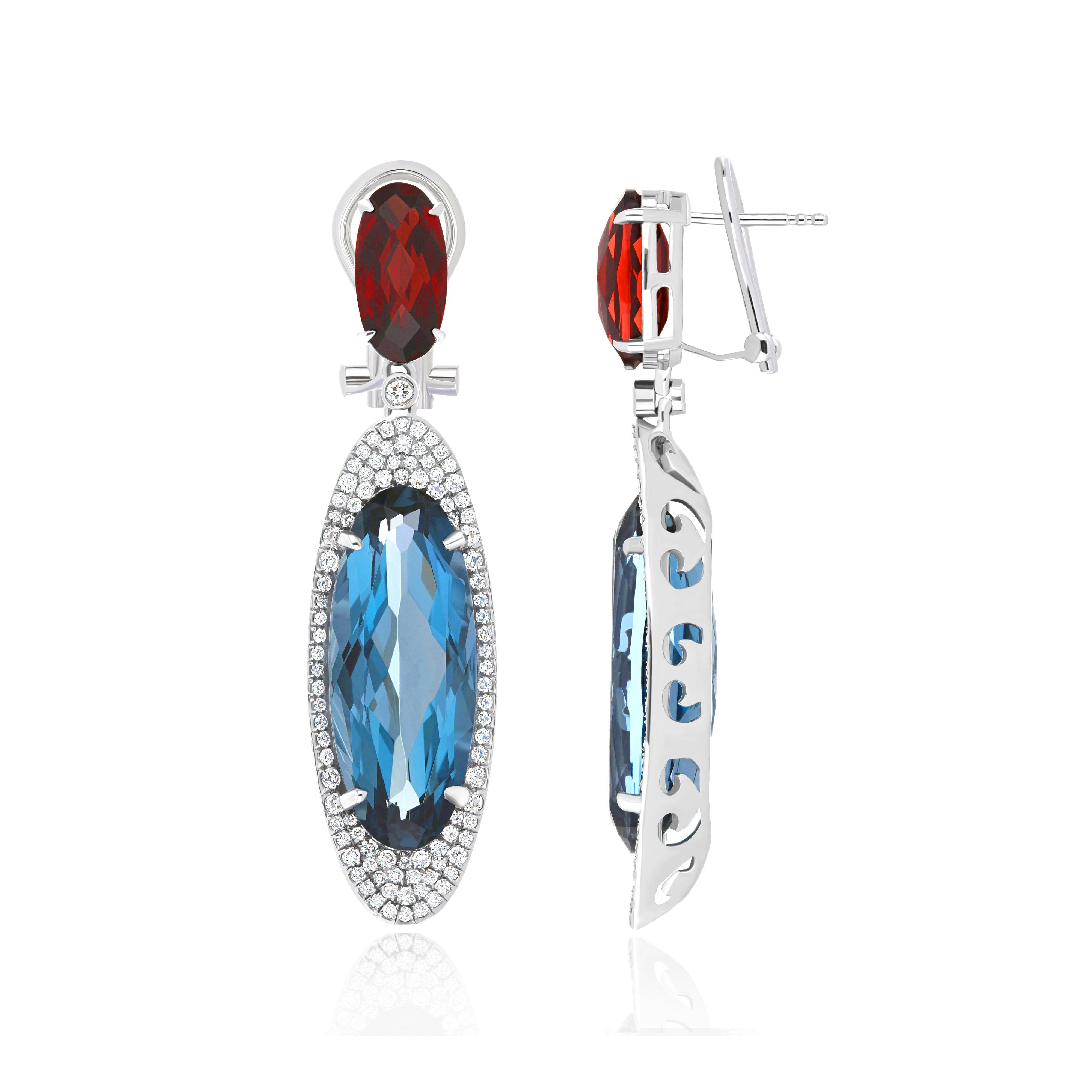 Elegant and exquisitely detailed Cocktail 14 Karat White Gold Earring, center set with 13.90Cts. (approx.) Fancy Elongated Oval Shape London Blue Topaz, accented with Elongated Oval Garnet 3.32Cts (approx.) Surrounded with micro pave Diamonds,